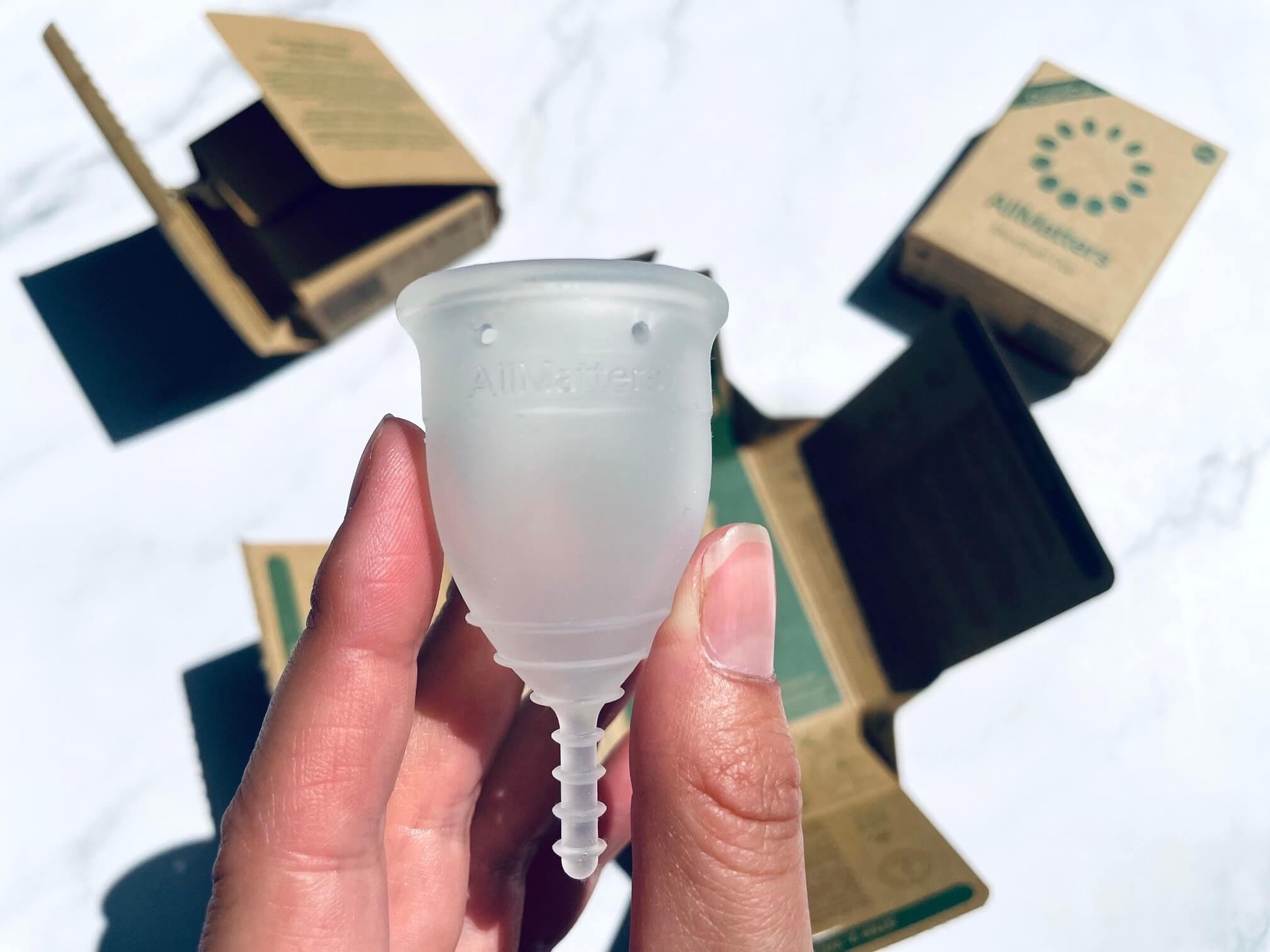 AllMatters menstruationskop i hånd foran flere menstruationskopper