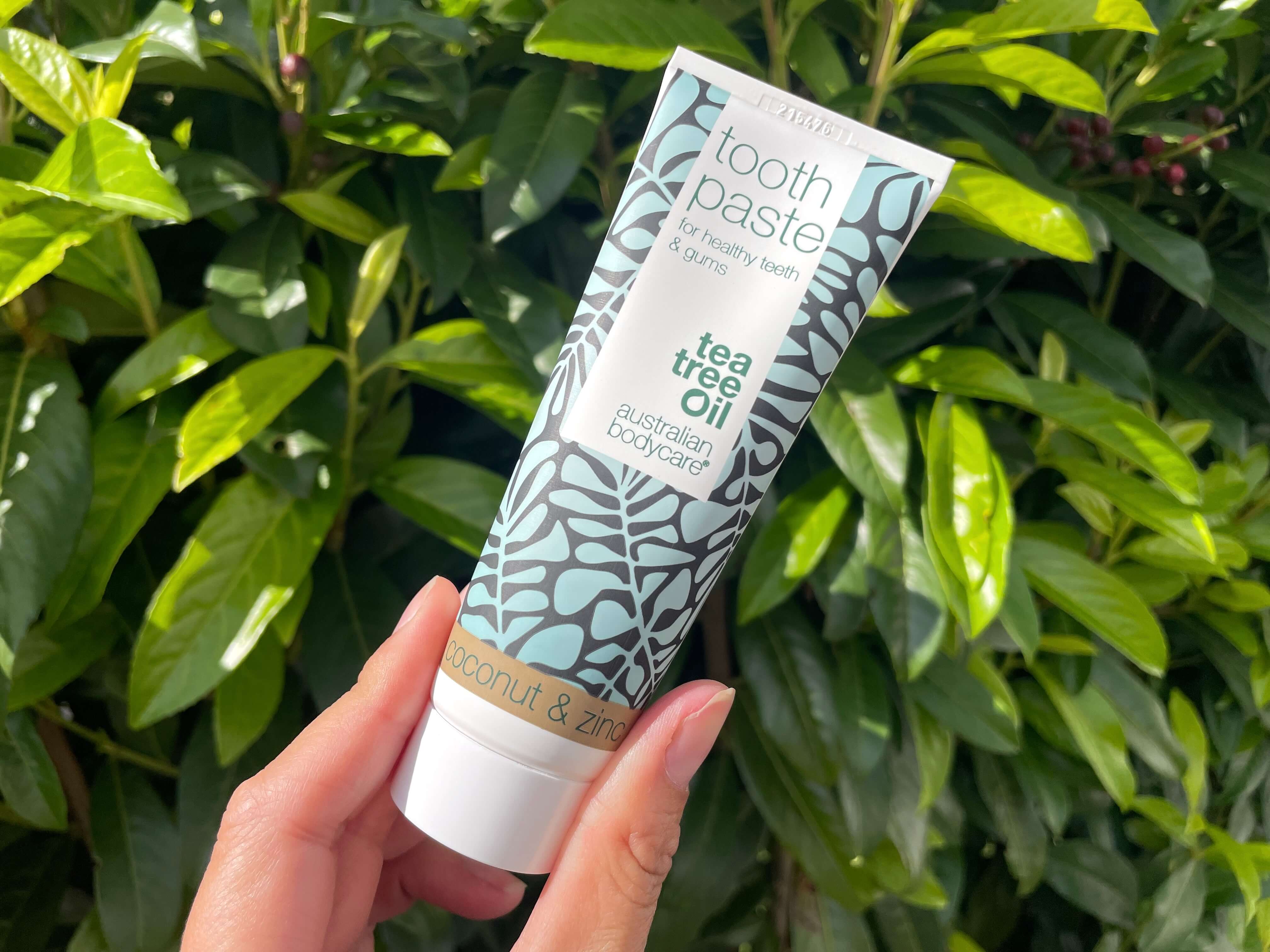 Australian Bodycare tandpasta med Kokos og Zink i hånd foran hæk