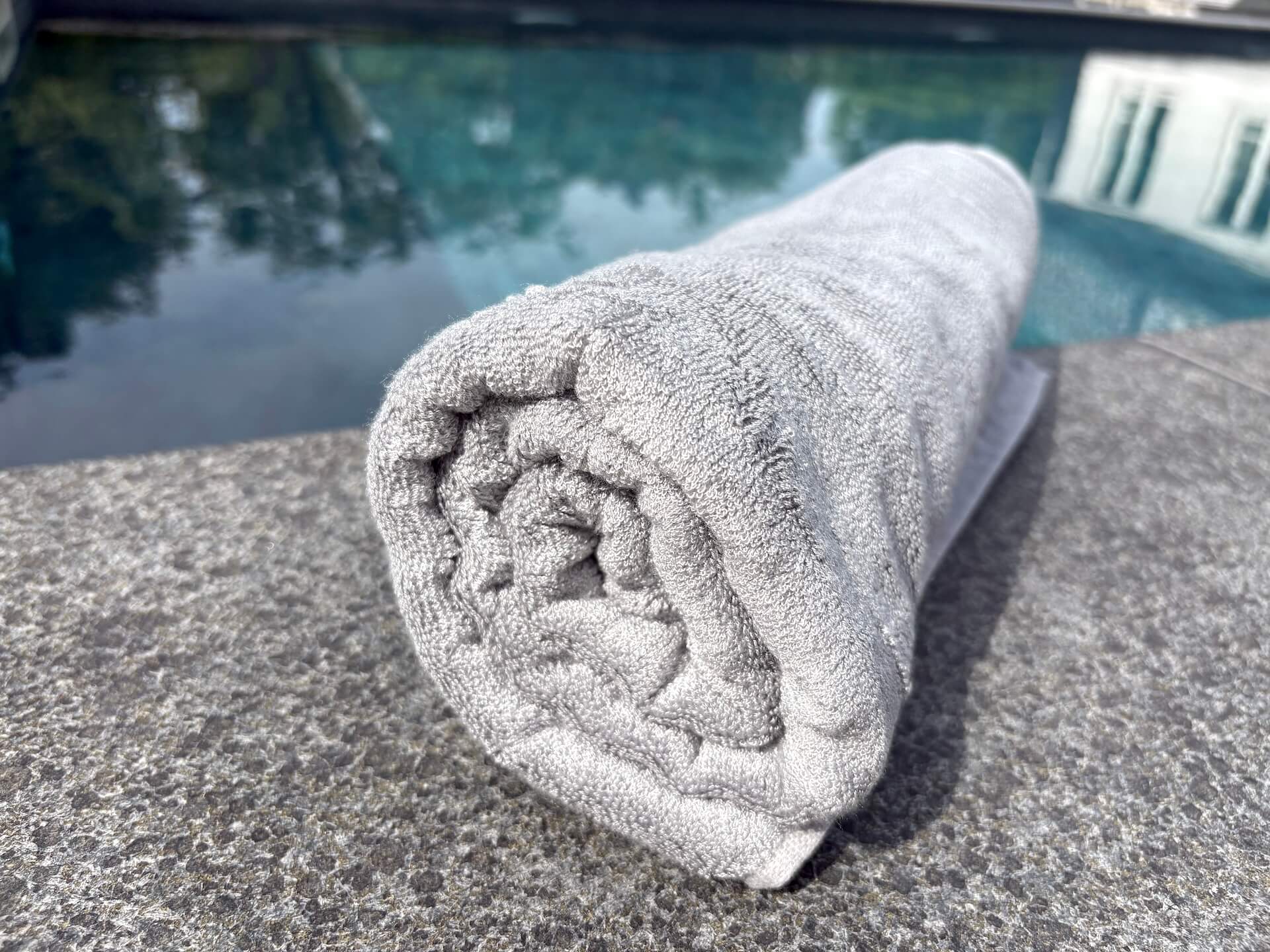 Bambuni badehåndklæde 70x140 rullet sammen foran pool
