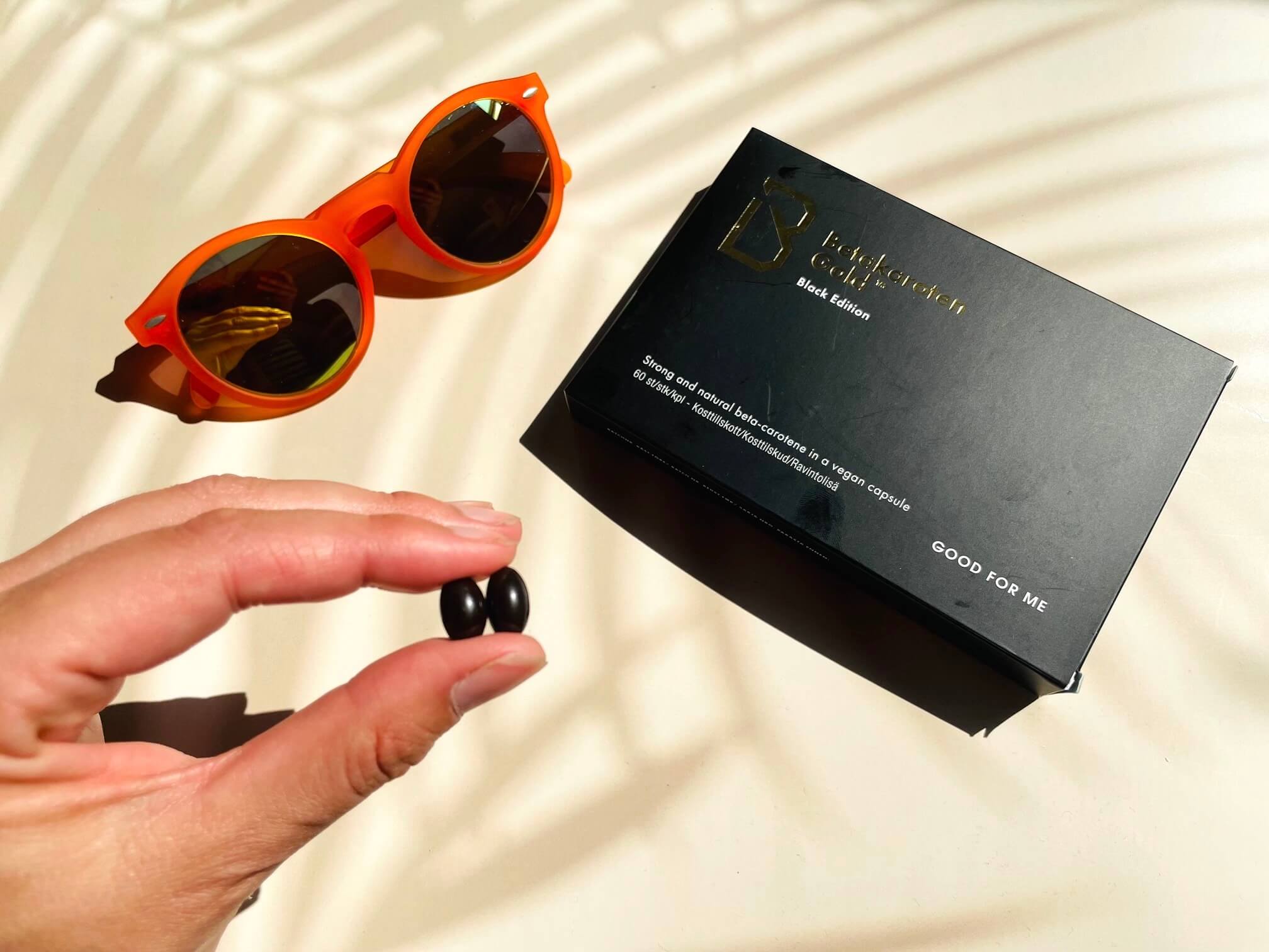 Betakaroten Gold black edition tablet imellem fingrene på kvinde