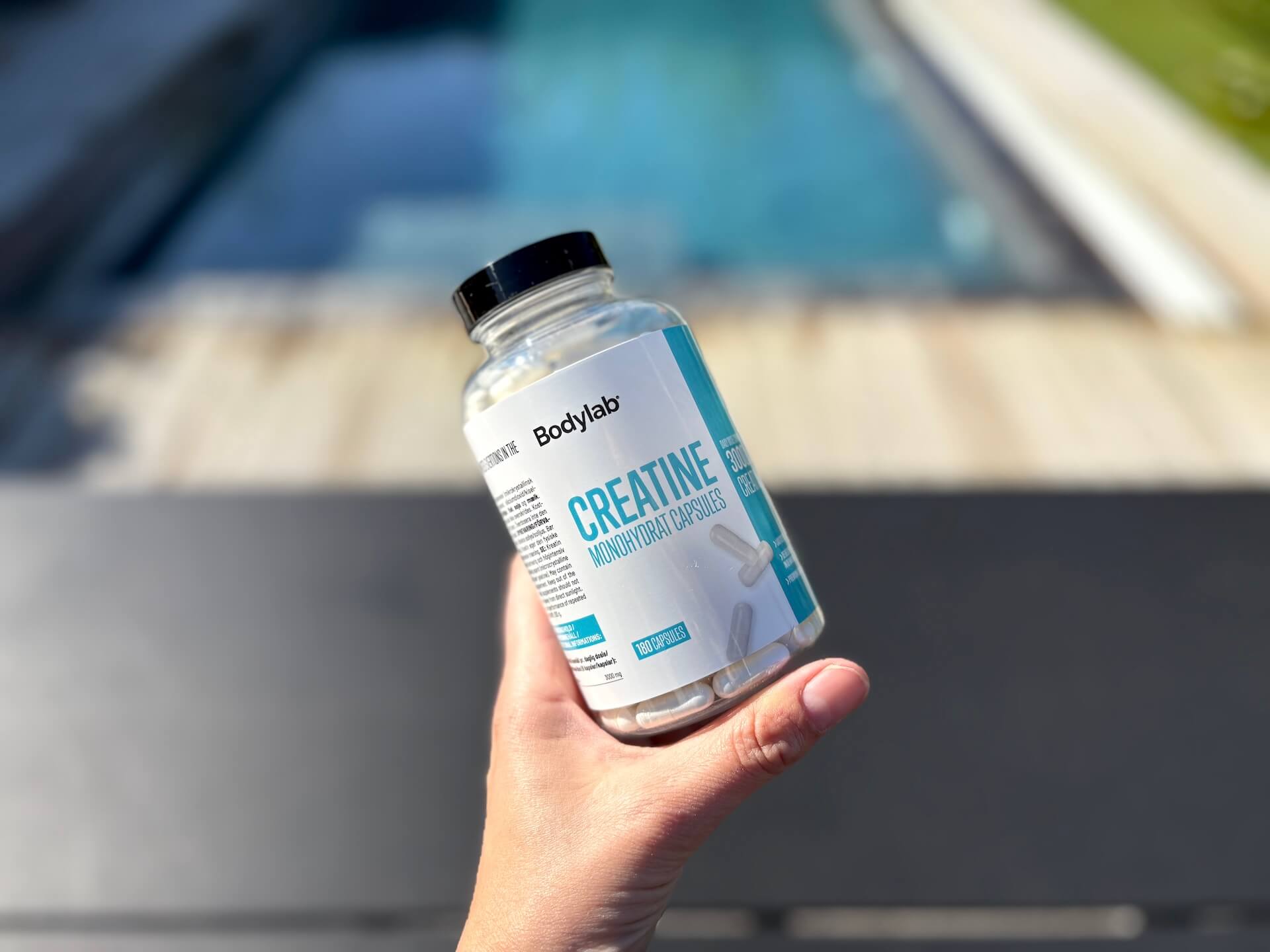 Bodylab Creatine Capsules i hånd ved pool