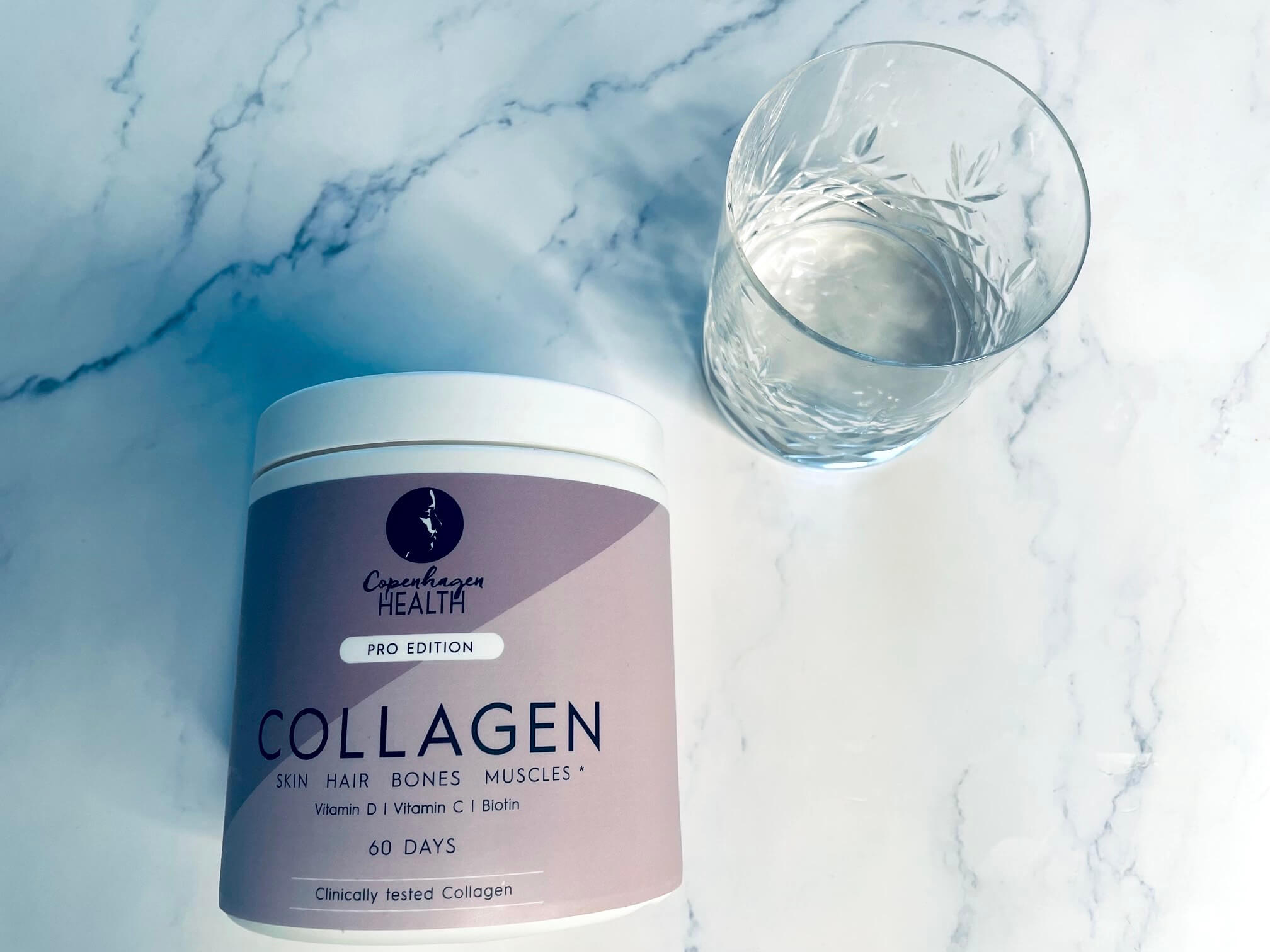 Bovine Collagen Pro Edition fra Copenhagen Health på bord med glas