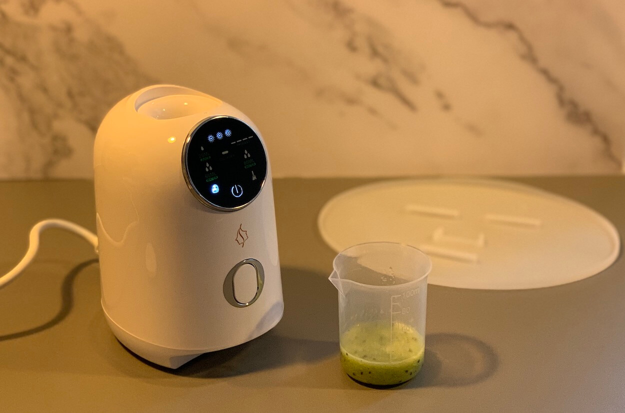 Comforth Mask Machine ansigtsmaskemaskine på et bord med blendet kiwi