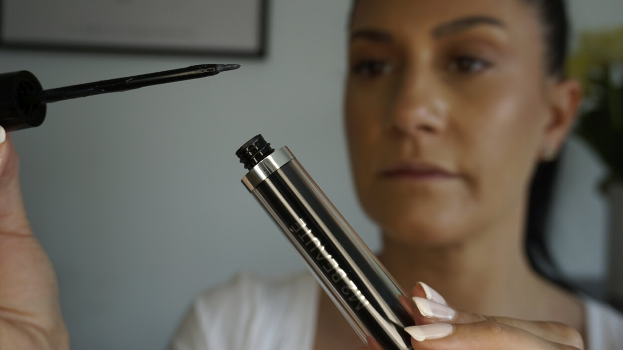 Kvinde trækker applikator op af M2 øjenvippeserum