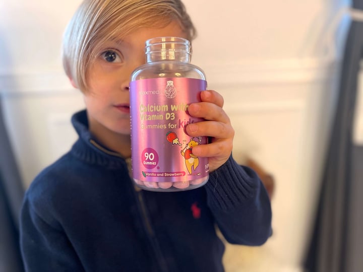 Dreng der holder bøtte med Kalk + D3-vitamin vingummi foran ansigtet