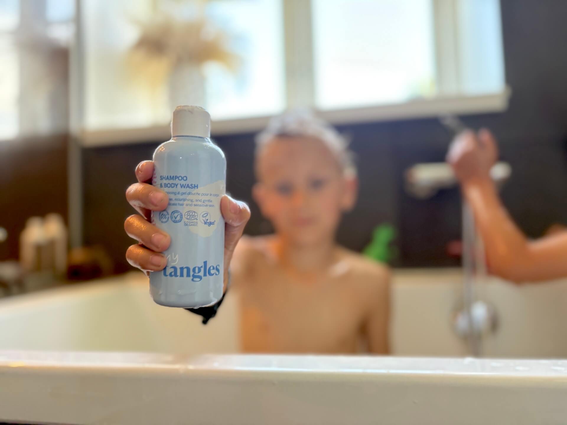 Dreng i bad med Hairlust Tiny Tangles Shampoo & Body Wash i hånden