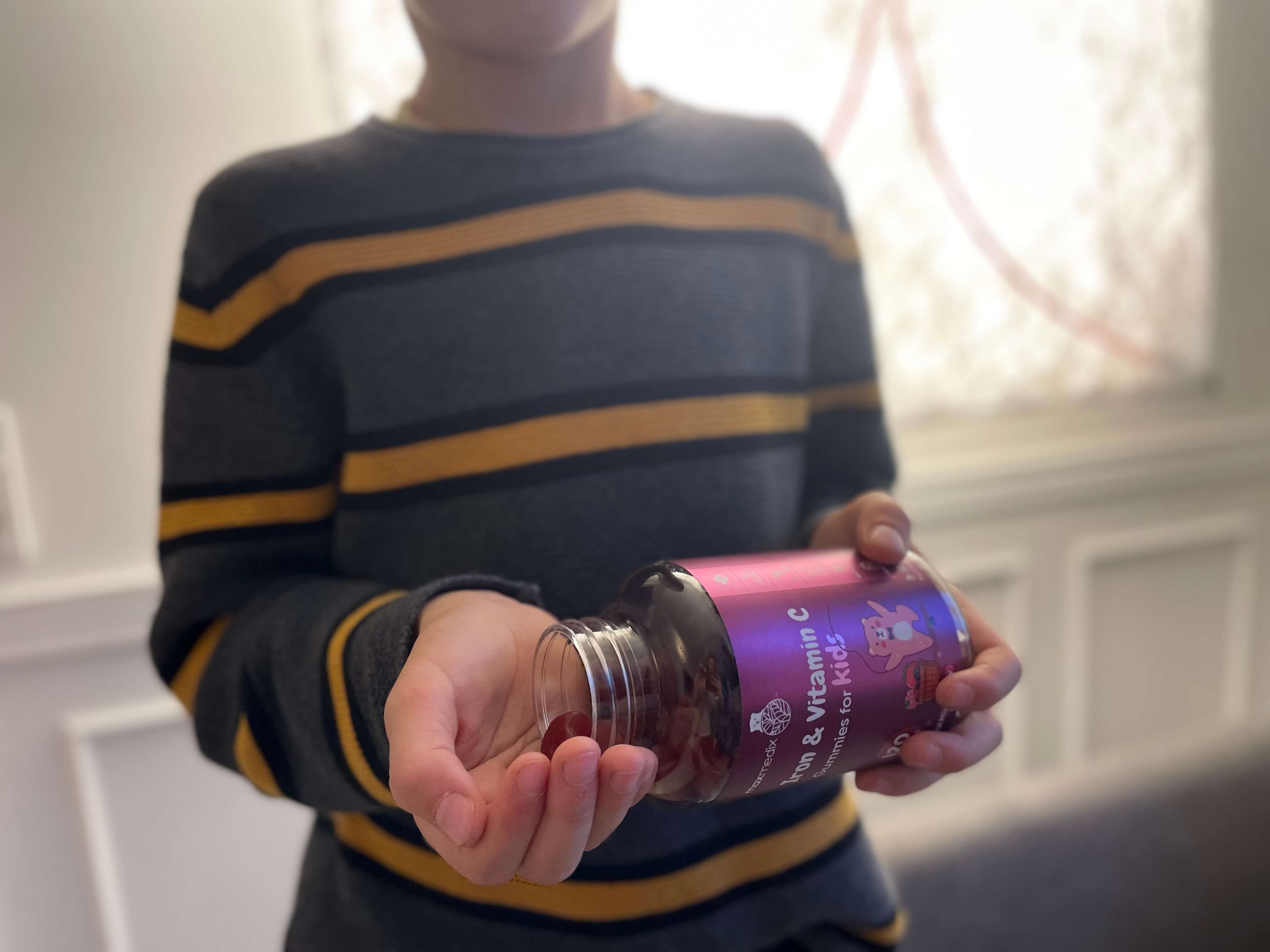Dreng med jern og C-vitamin vingummier til børn i bøtte i hånd