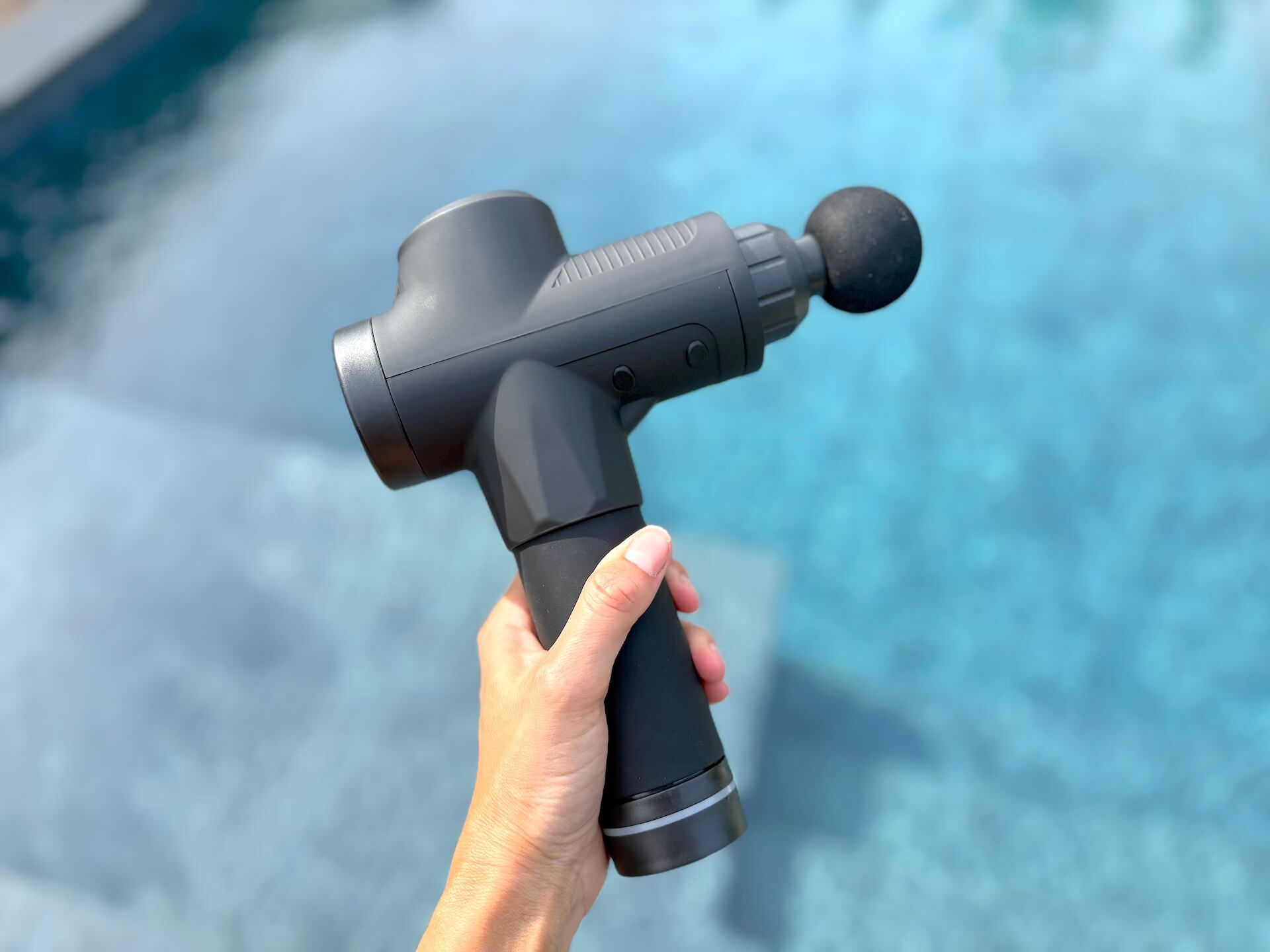 Fitnessfree Massagepistol PRO i hånd over pool