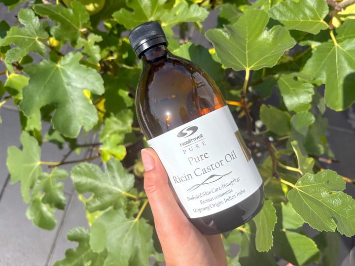 Flaske med Healthwell PURE Ricinus Castor olie ØKO i hånd