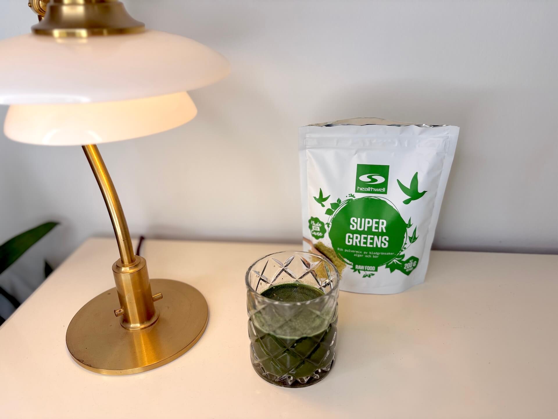 Glas med opløst Healthwell Super Greens på bord