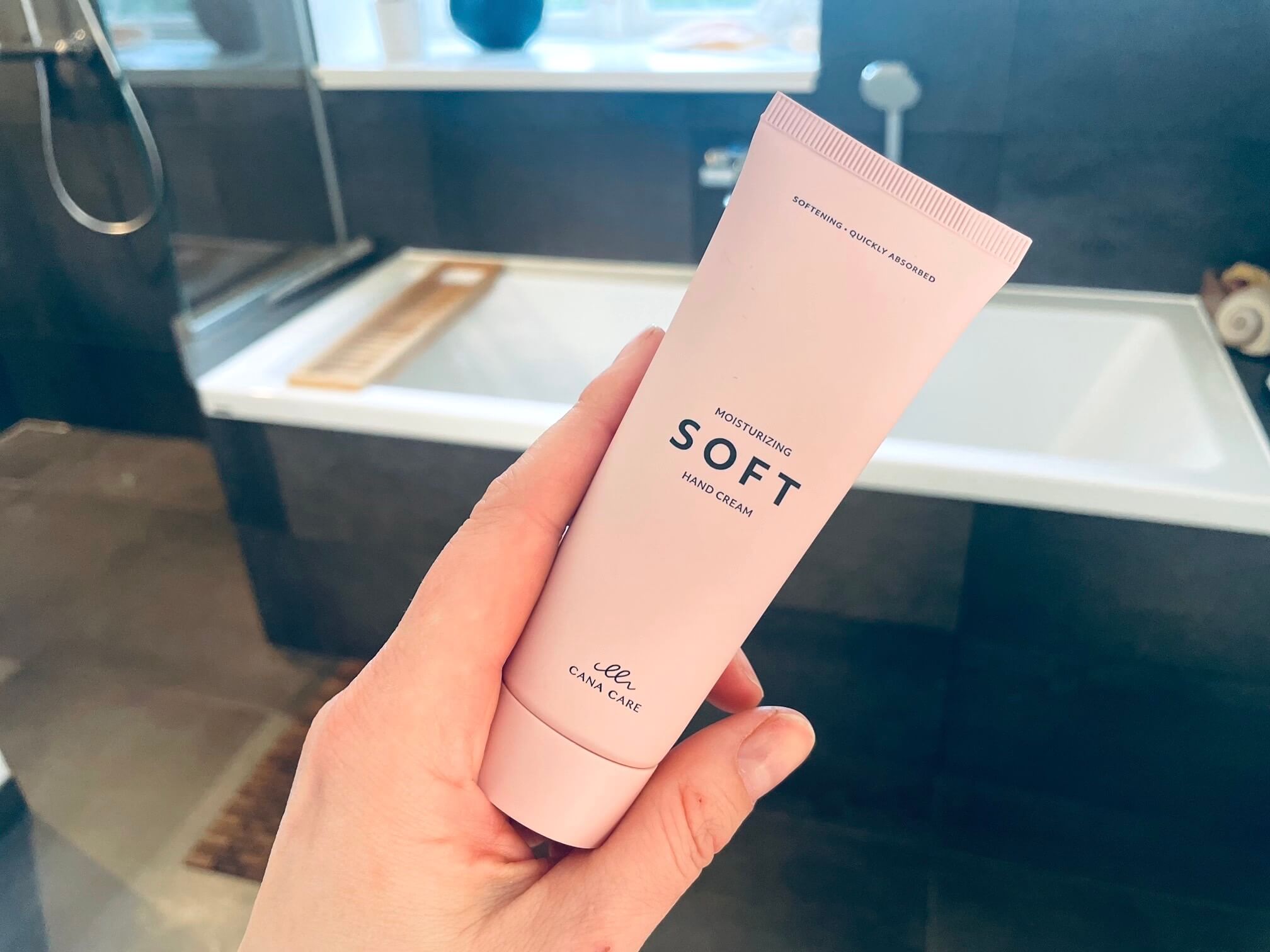 Hånd med SOFT hand cream fra Cana Care på badeværelse