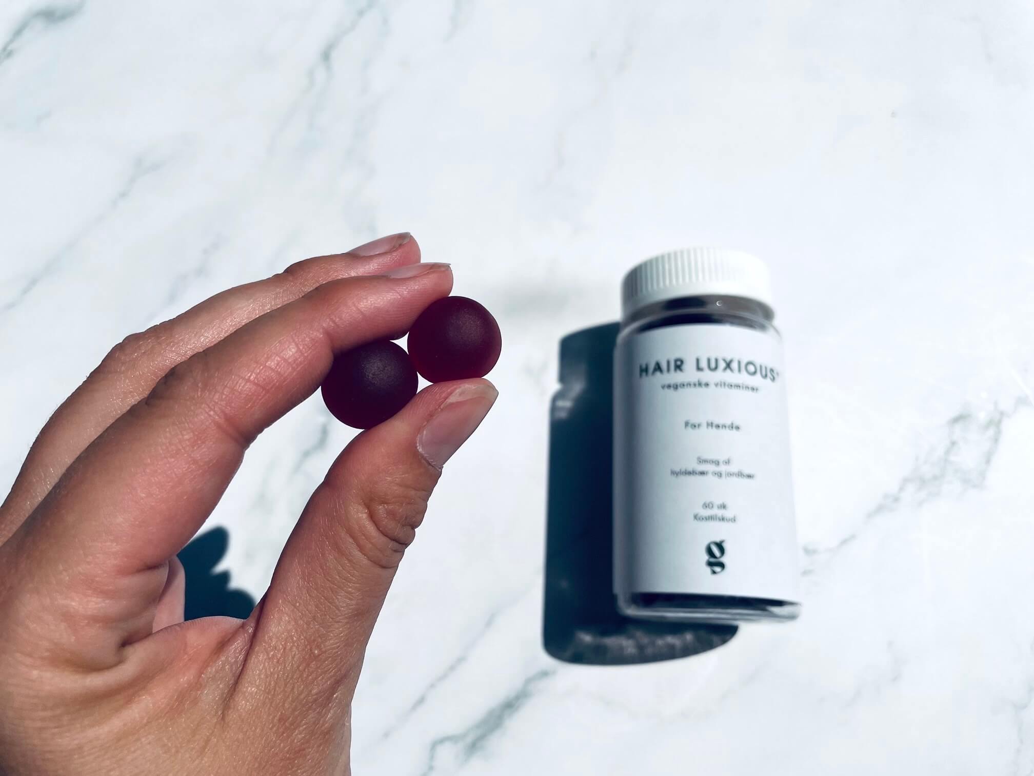 Hårvitaminer som vingummier i hånden på kvinde