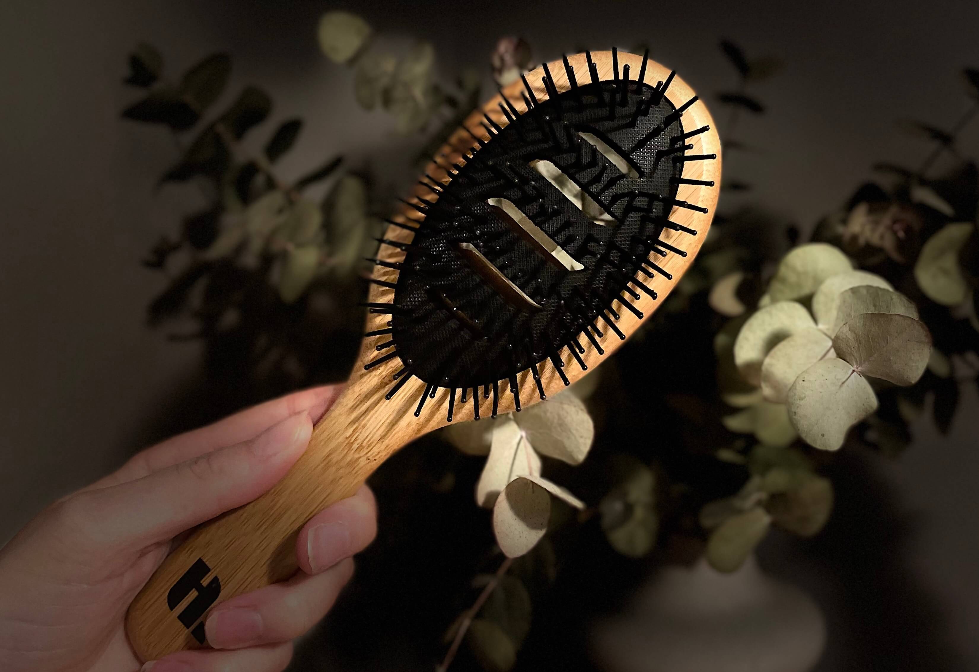 Hairlust Bamboo Vented Brush i en hånd med plante i baggrund