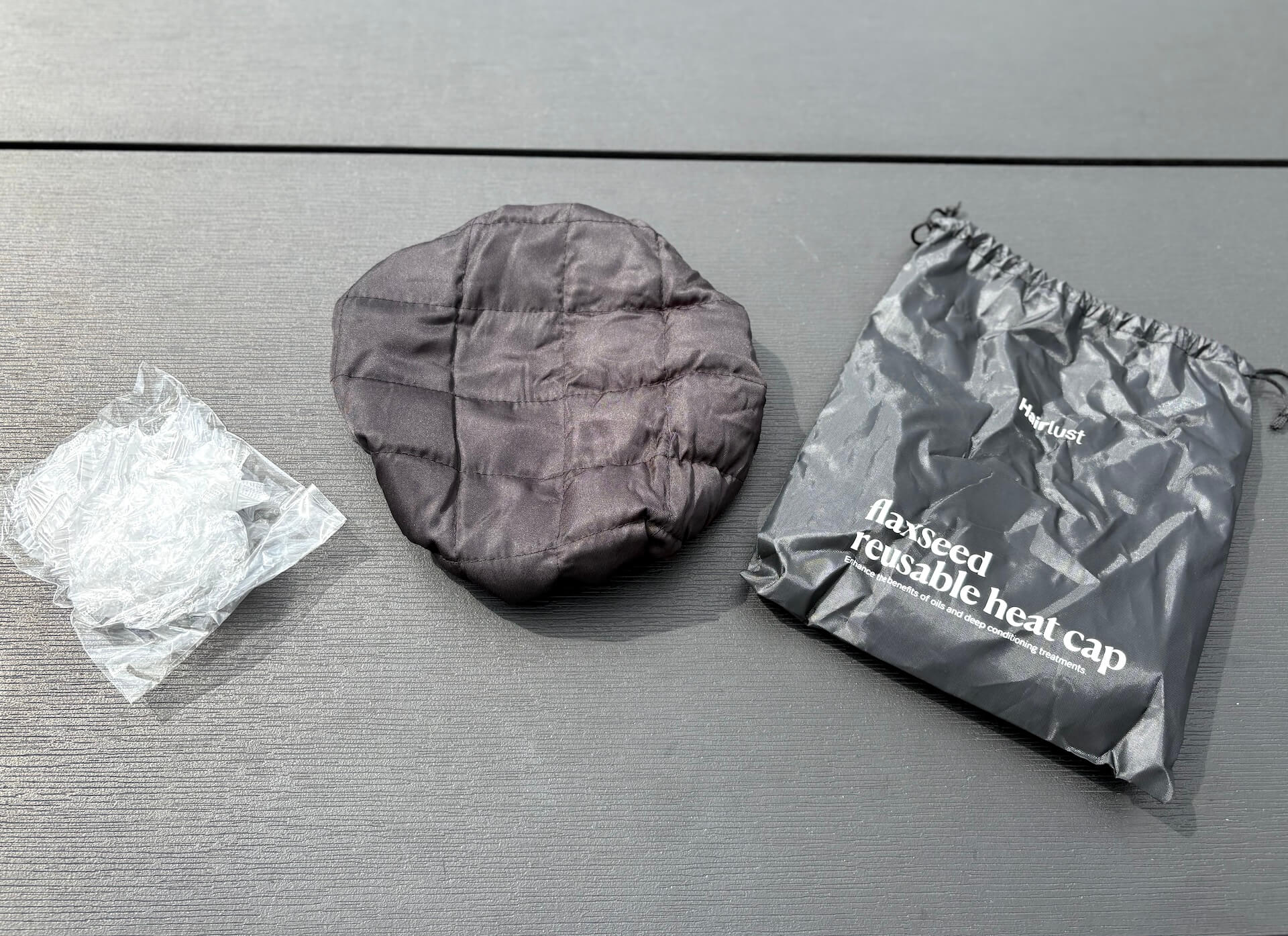Hairlust Flaxseed Reusable Heat Cap og plasthætter og opbevaringspose på bord