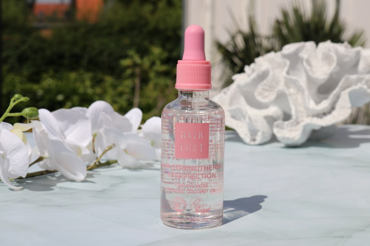 Hairlust hårolie på bord med blomster og koraller