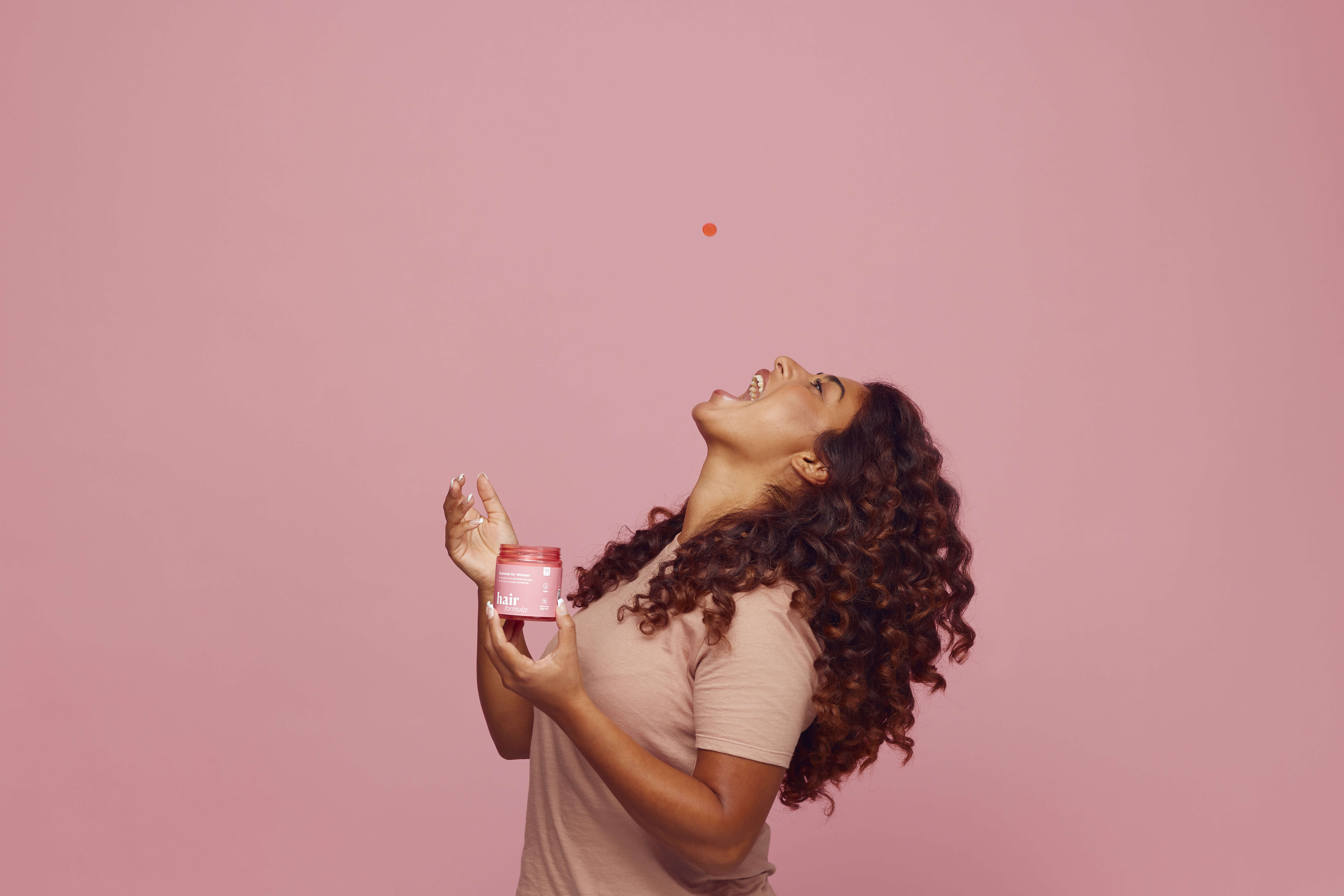 Hairlust Hair Formula Gummies der bliver kastet i munden på en kvinde