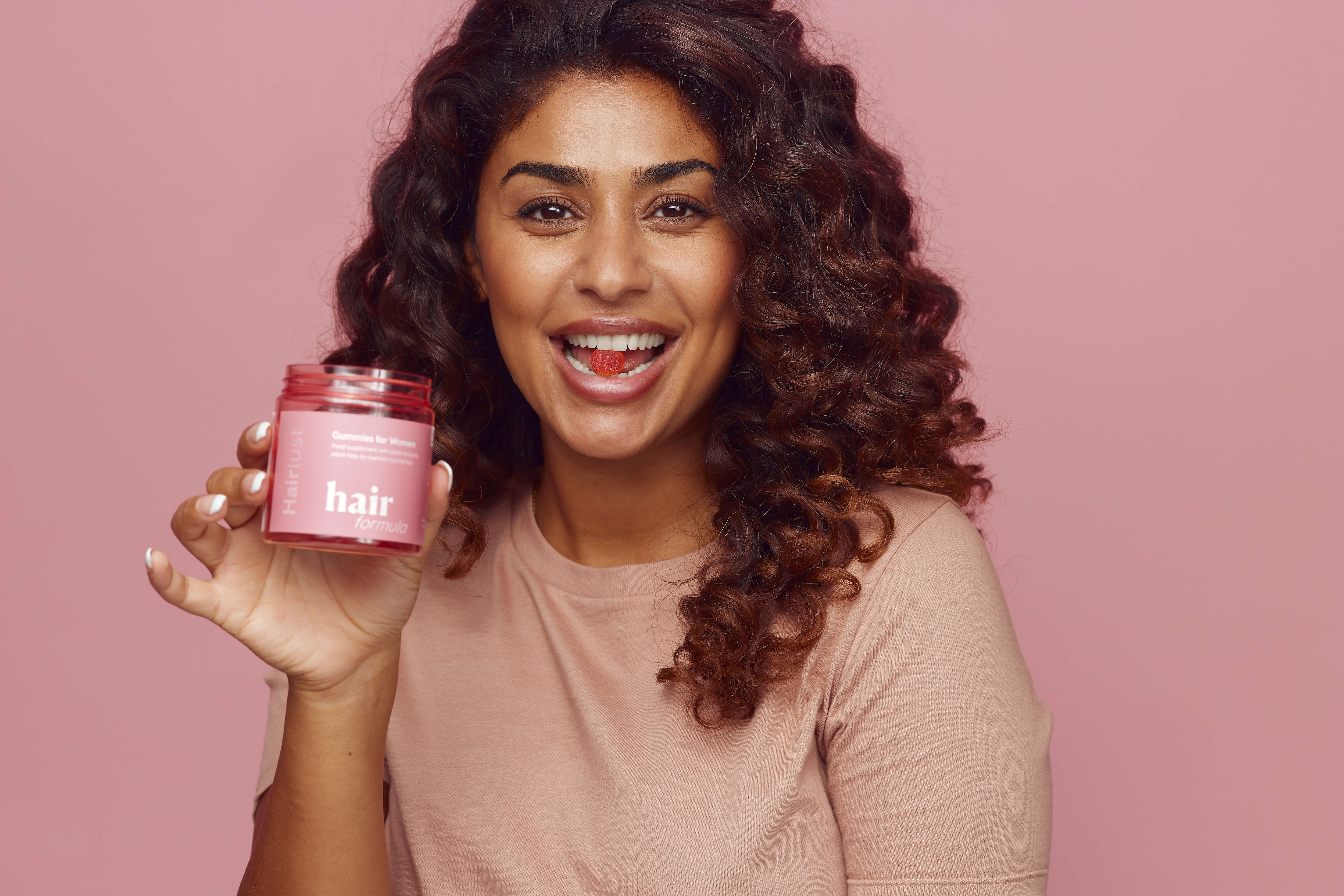 Hairlust Hair Formula Gummies i munden på mørkhåret kvinde