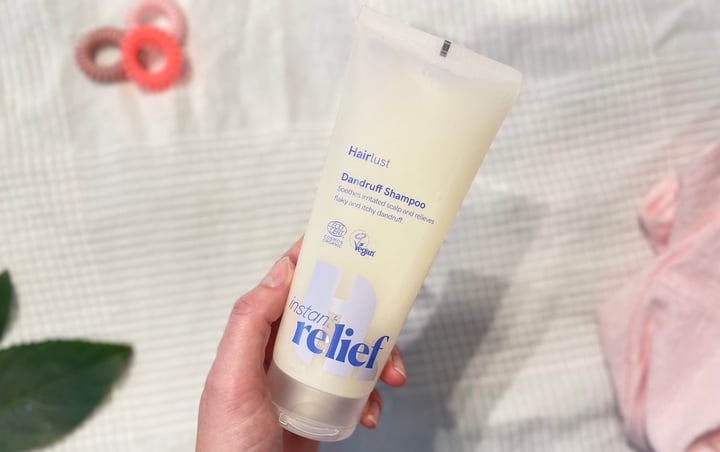 Hairlust Instant Relief skælshampoo i en hånd