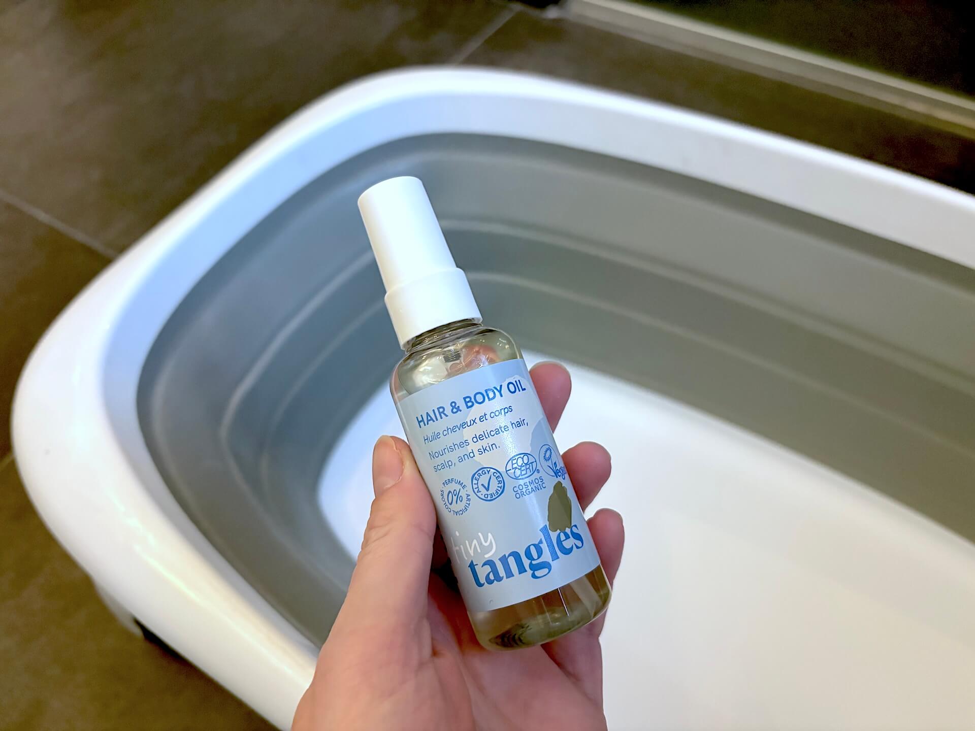 Hairlust Tiny Tangles Hair & Body Oil i hånd over badekar