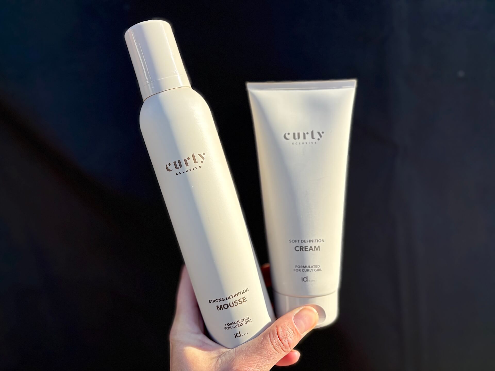 IdHAIR Curly Xclusive Strong Definition Mousse og krøllecreme i hånd