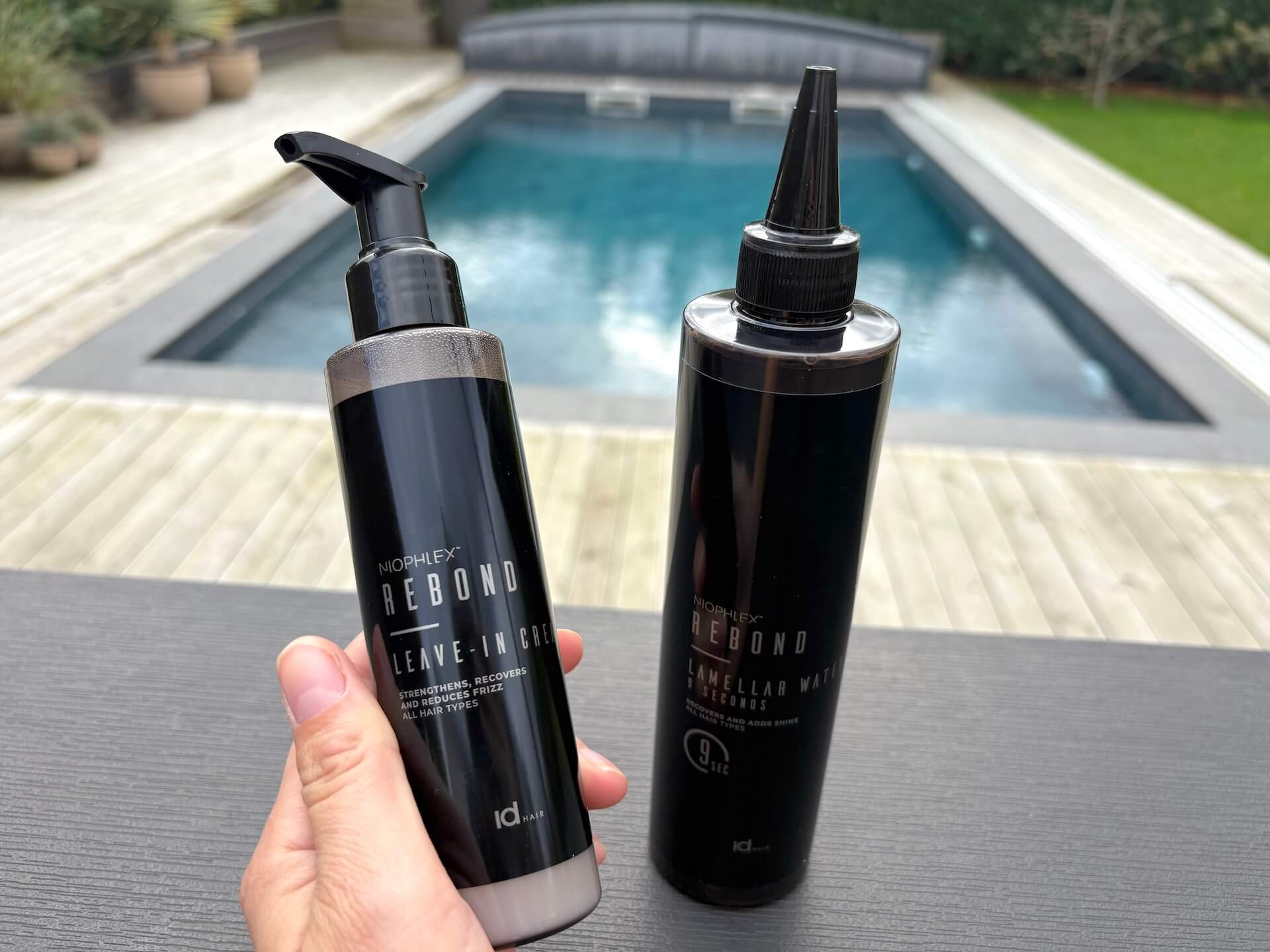 IdHAIR Niophlex Rebond Leave-In Cream i hånd med lamellar water i baggrund