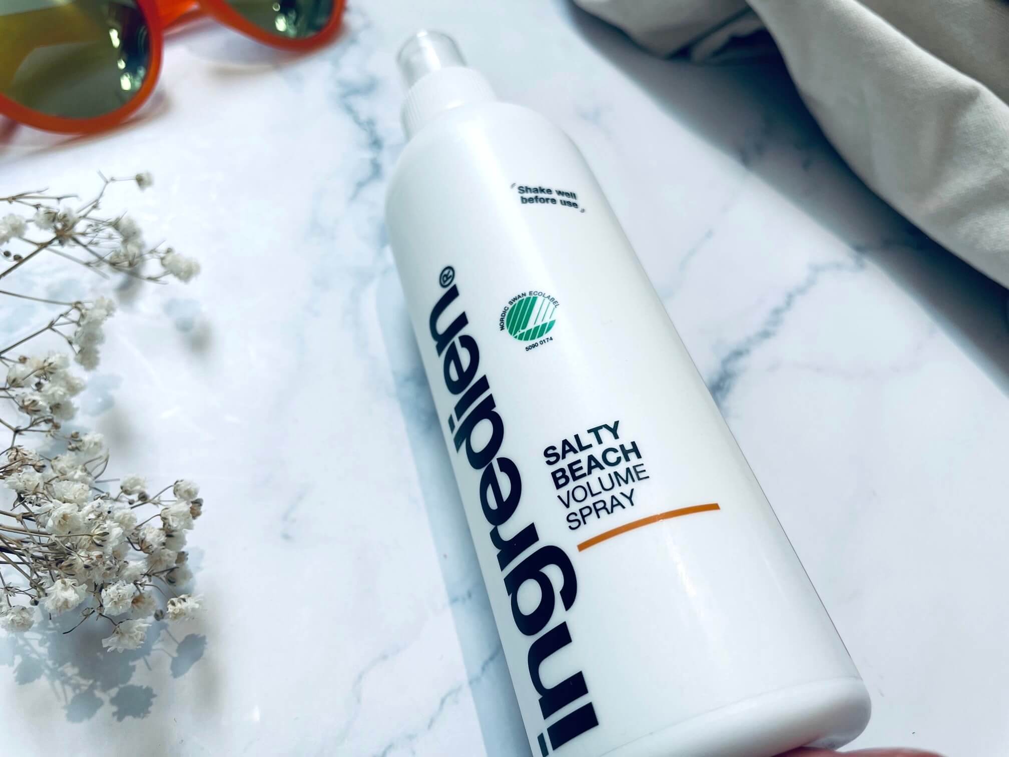 ingredien Salty Beach saltvandsspray på bord med blomst og solbriller