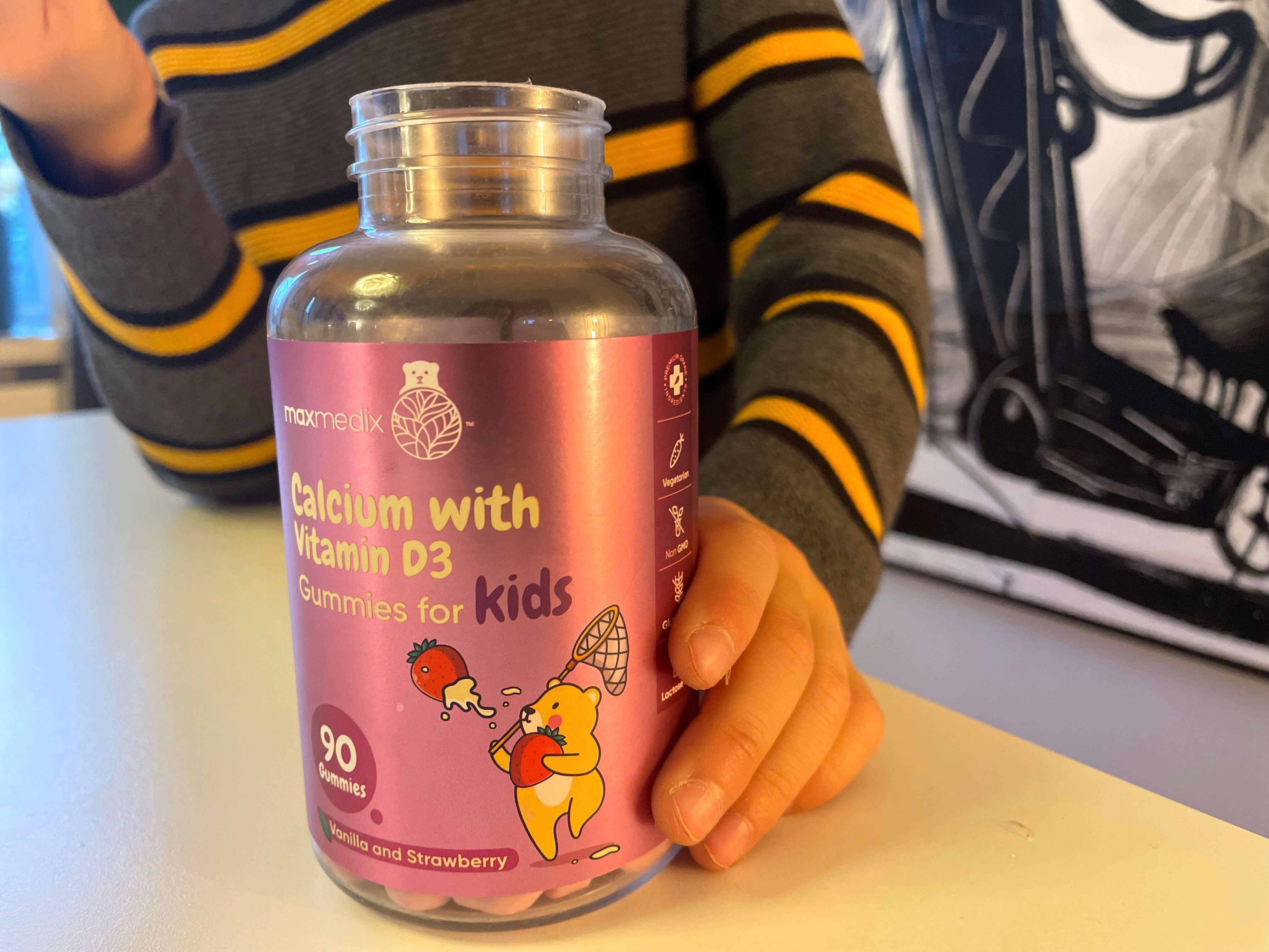 Kalk + D3-vitamin vingummi fra Maxmedix på bord i hånden på dreng