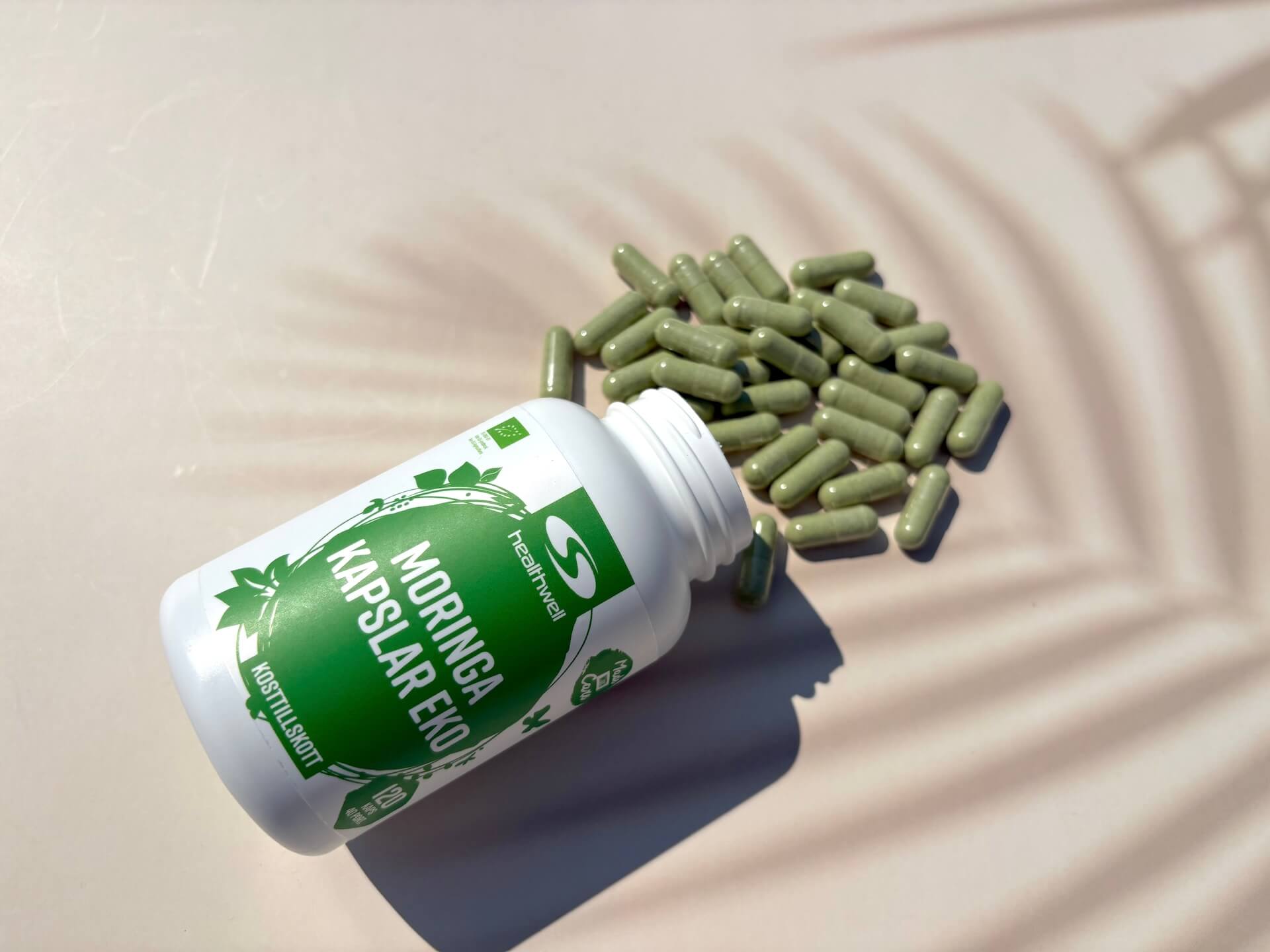Kapsler fra Healthwell Moringa Kapsler ØKO hældt ud på bord