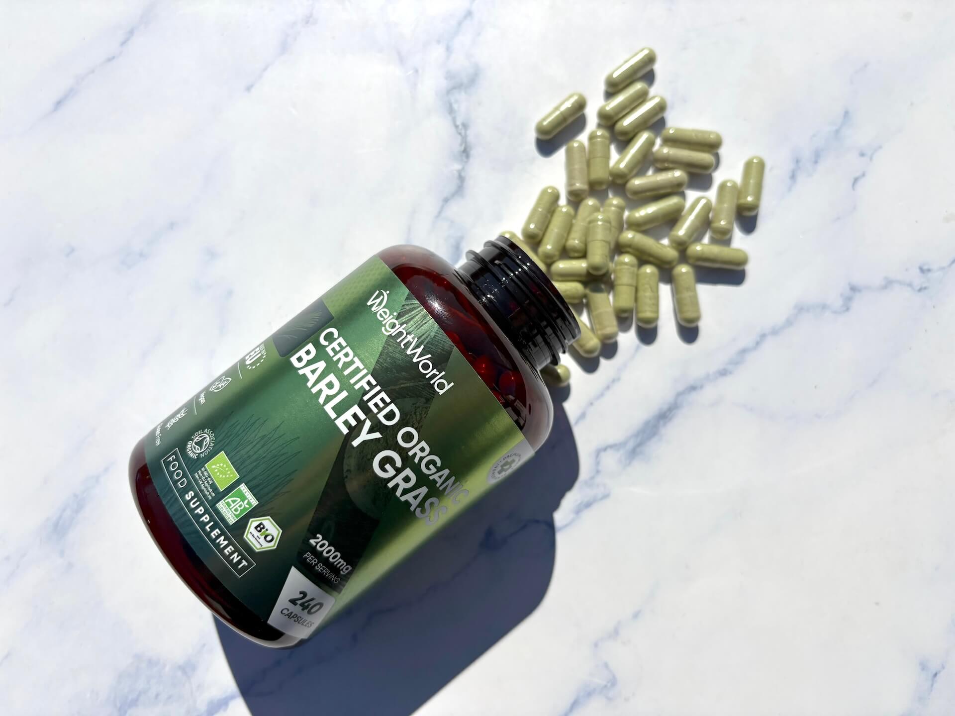 Kapsler hældt ud af Weightworld Certified Organic Barley Grass på bord