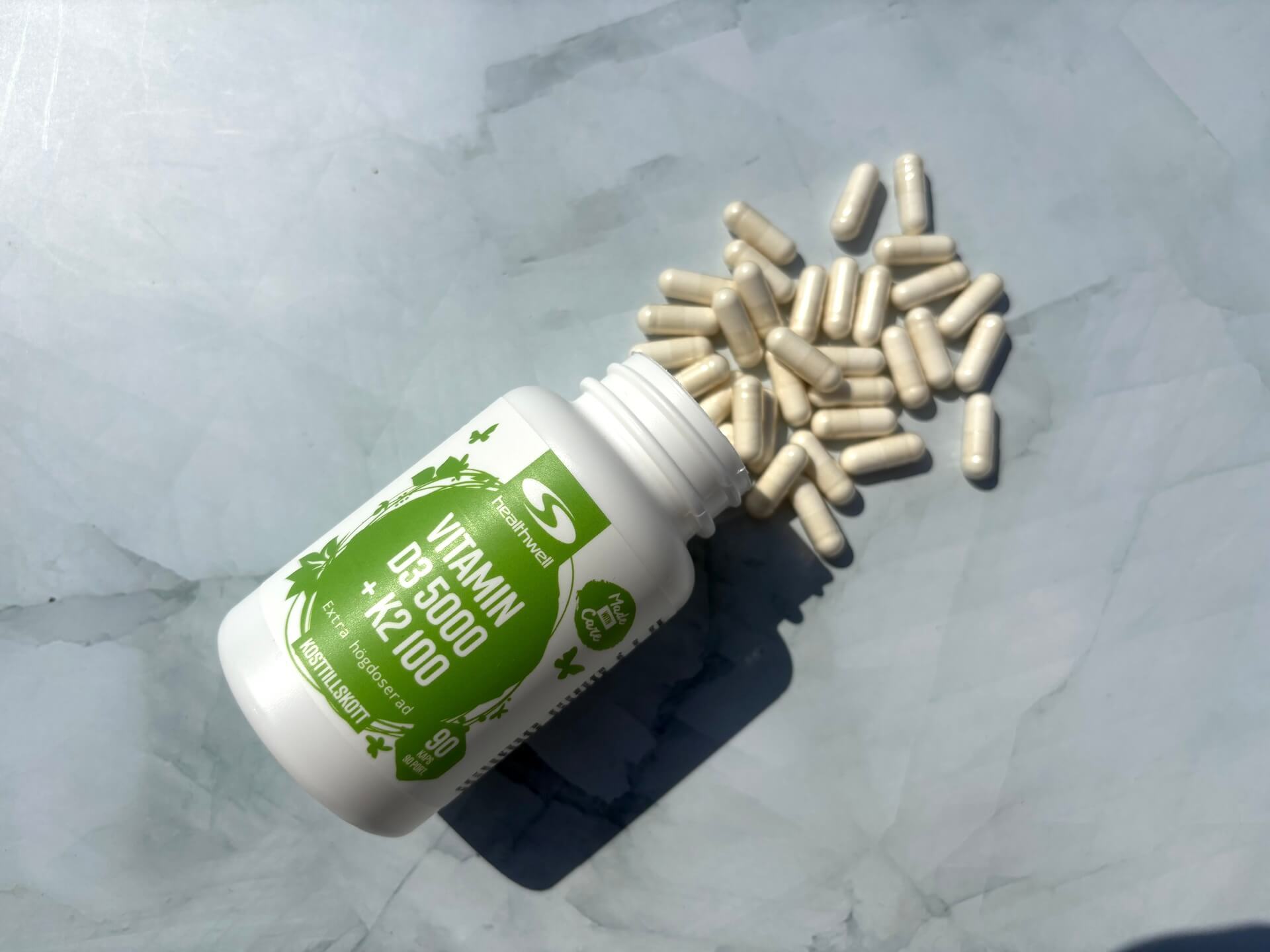 Kapsler i Healthwell Vitamin D3 5000 + K2 100 hældt ud på bord