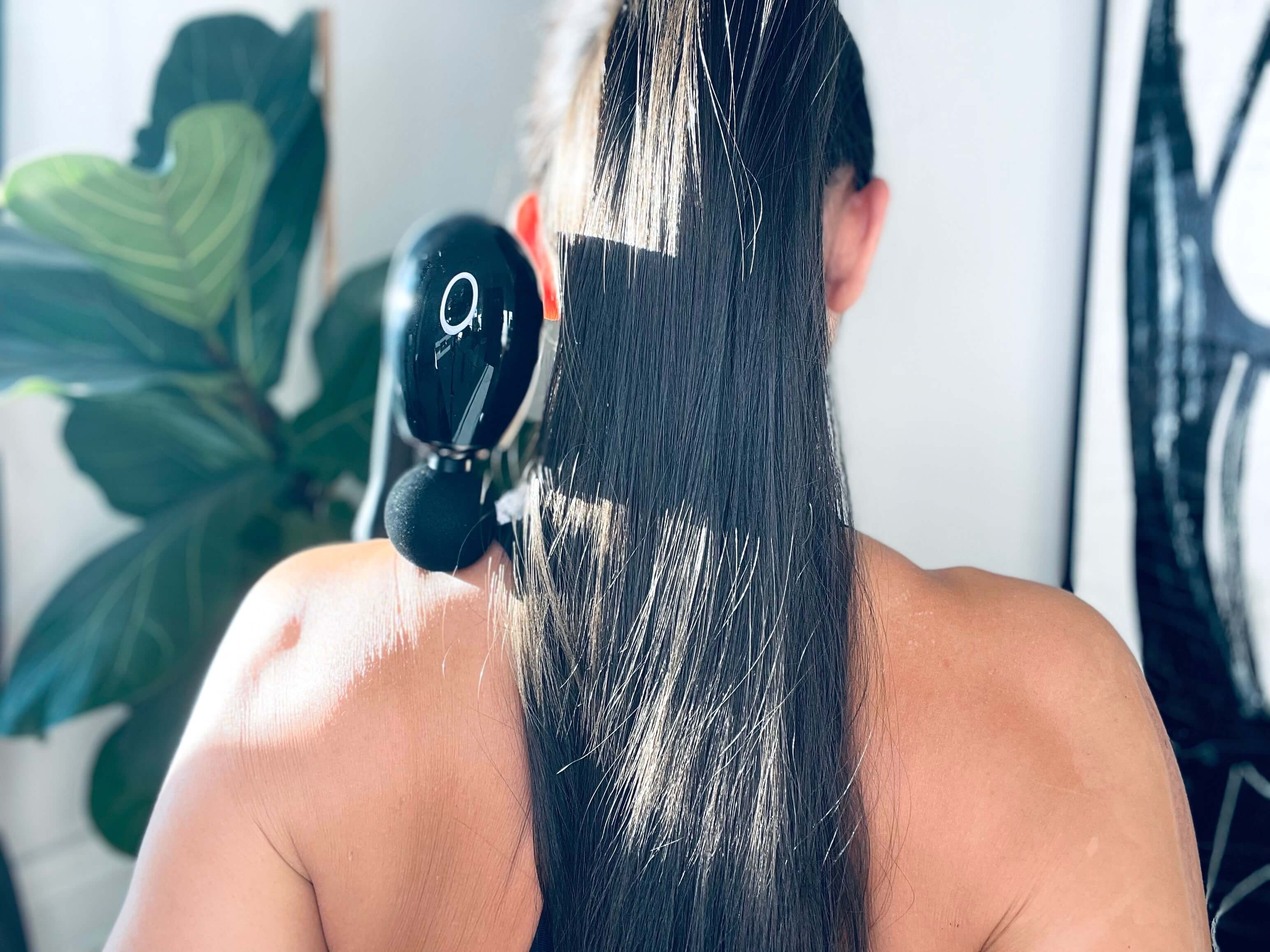 Kvinde bagfra med MassagePistol Twist i nakken