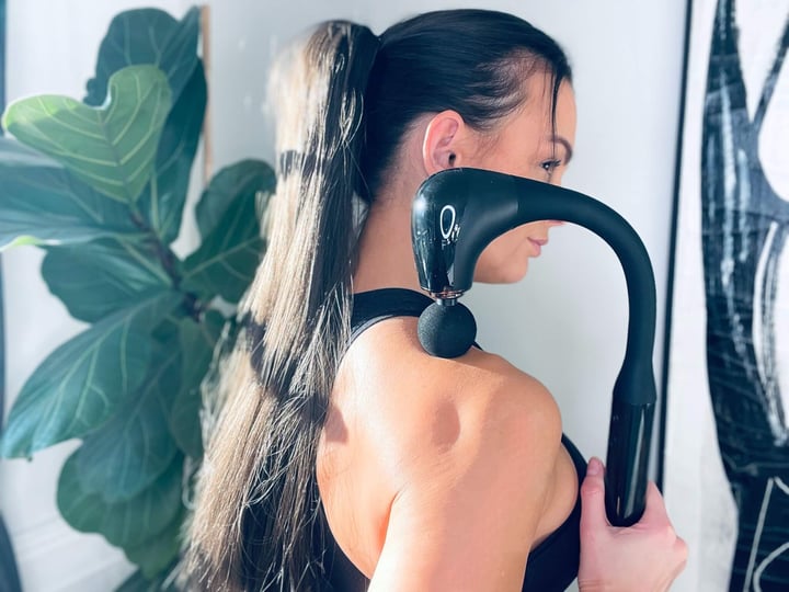 Kvinde der bruger MassagePistol Twist fra DeluxeCare i nakken