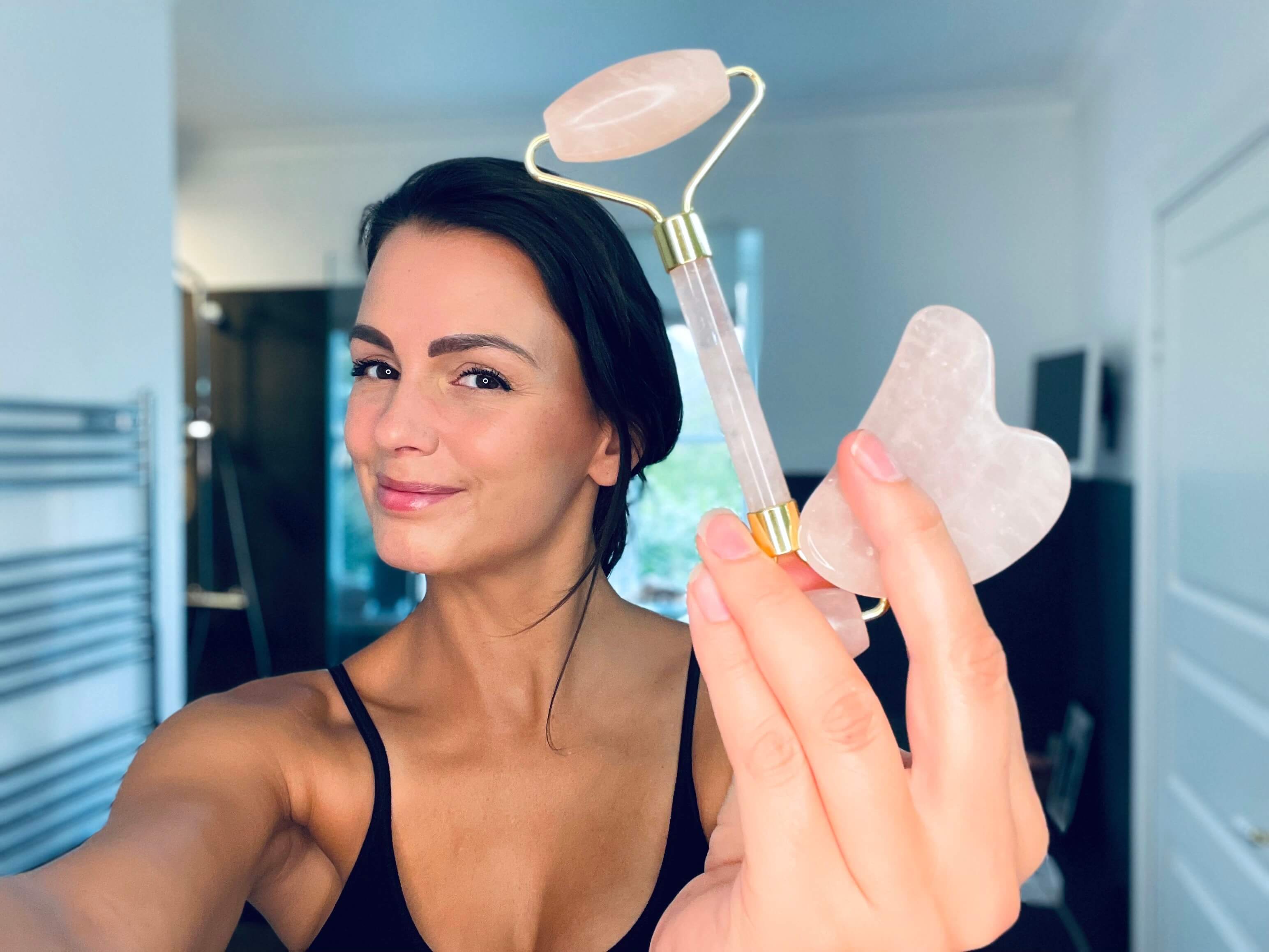 Kvinde der holder Comforth gua sha sæt med ansigtsruller