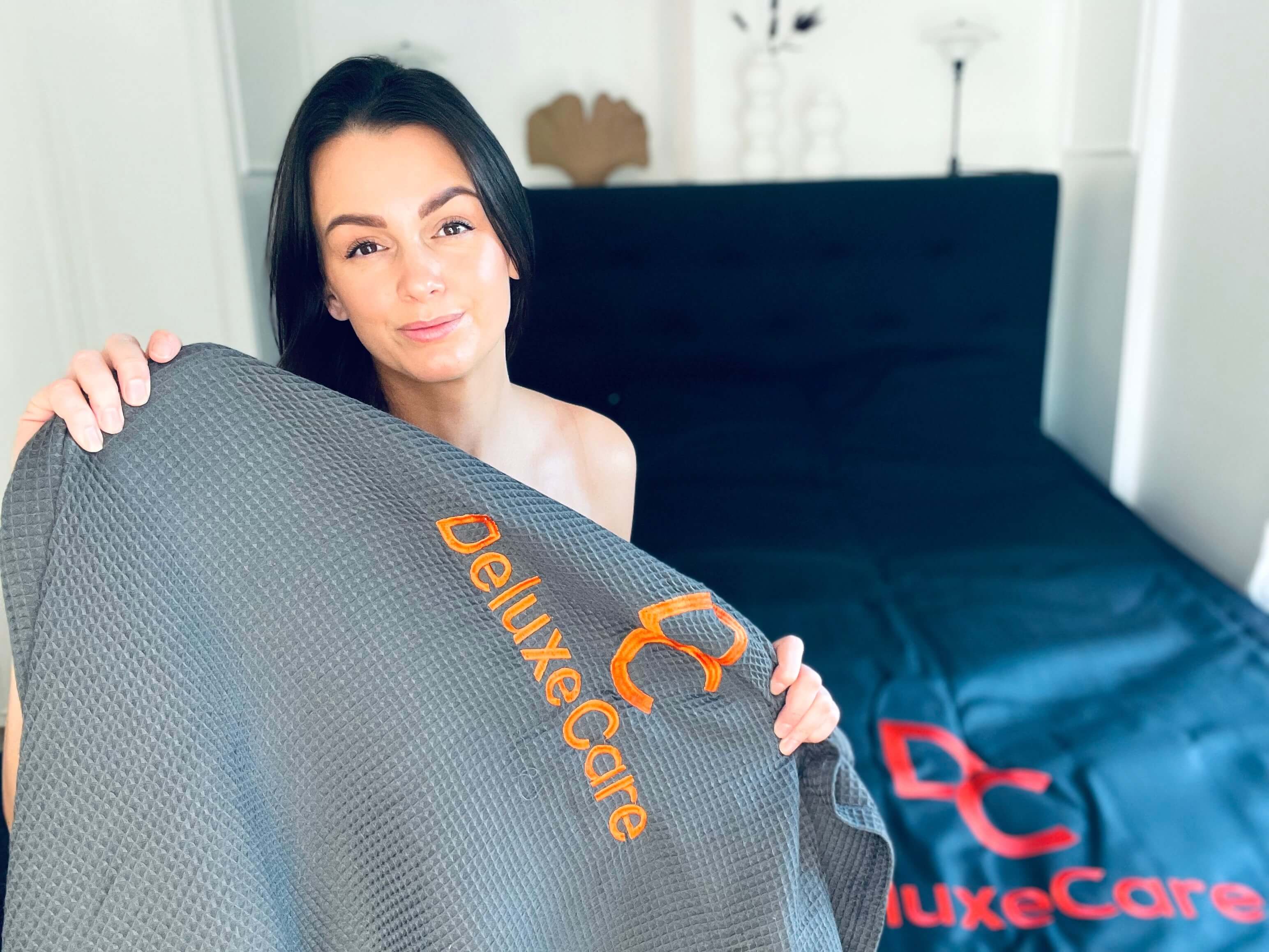 Kvinde der sidder med BodyCover til infrarød saunatæppe fra DeluxeCare