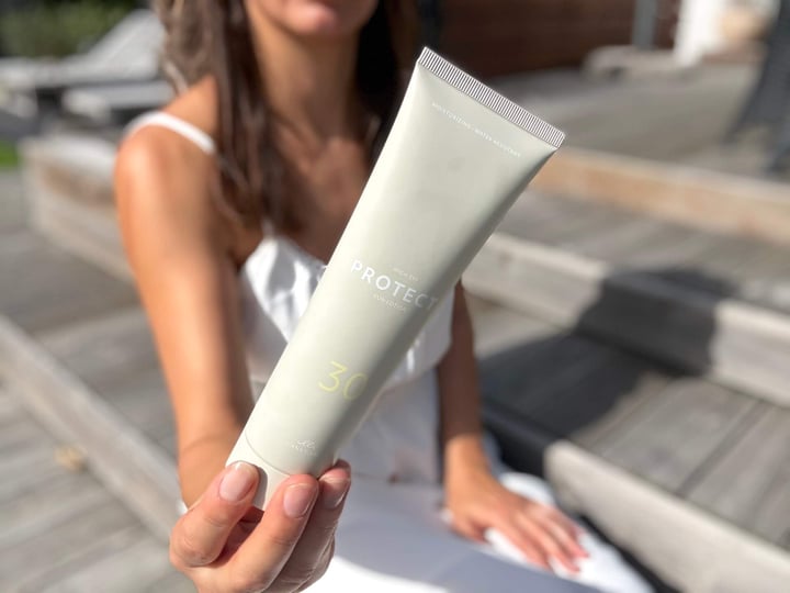 Kvinde der sidder med Cana Care PROTECT Sun Lotion SPF30