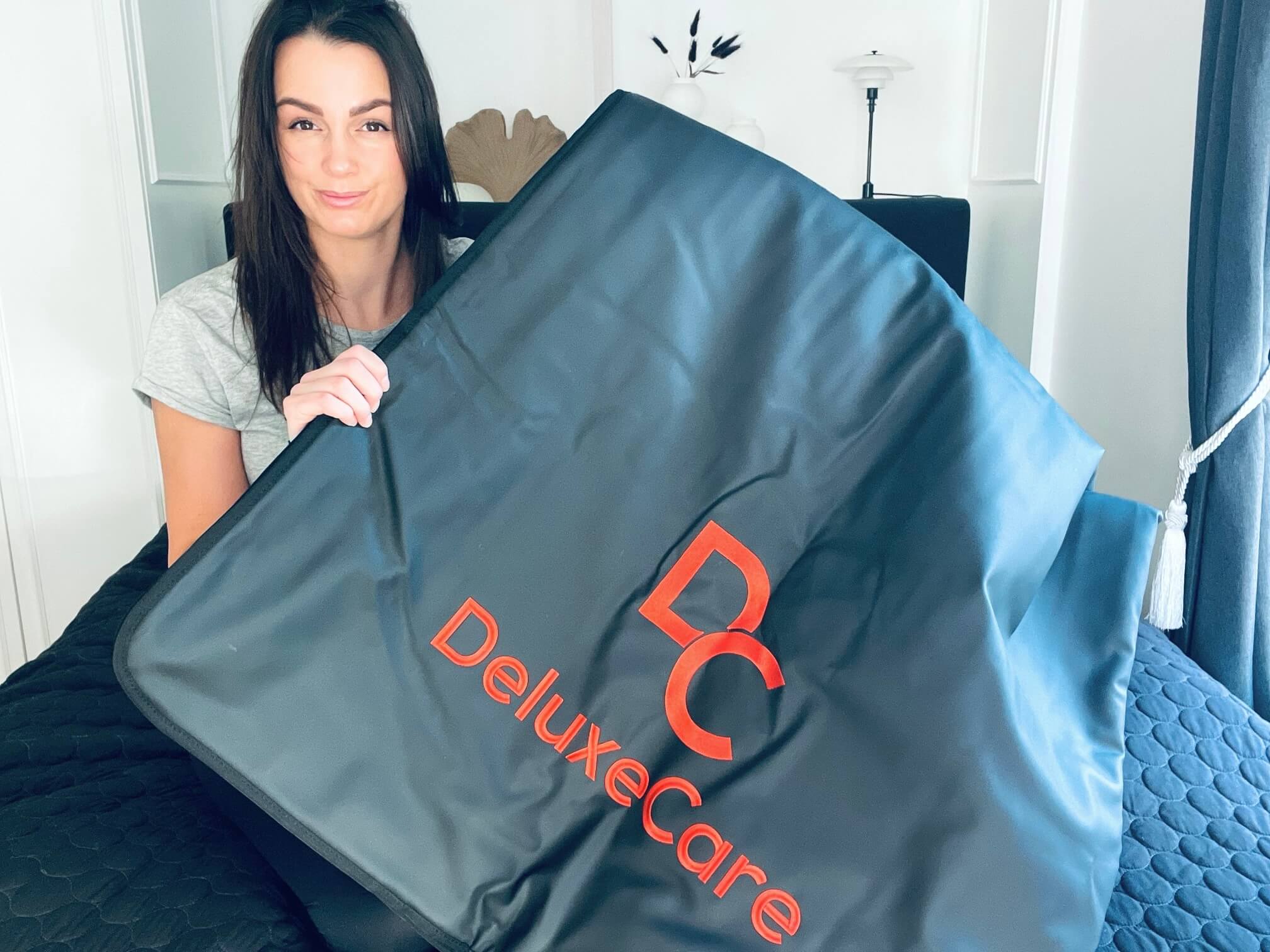 Kvinde der sidder med DeluxeCare infrarød saunatæppe