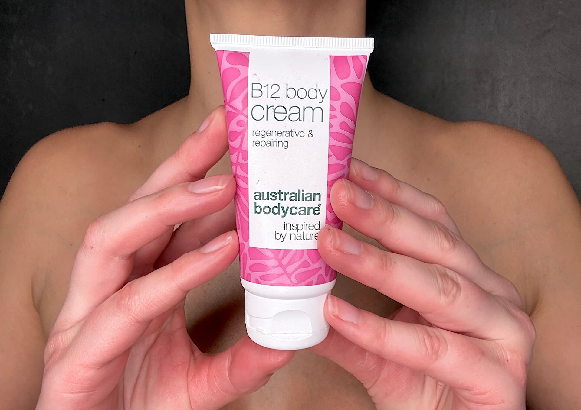 Kvinde der står med Australian Bodycare B12 Body Cream foran sig