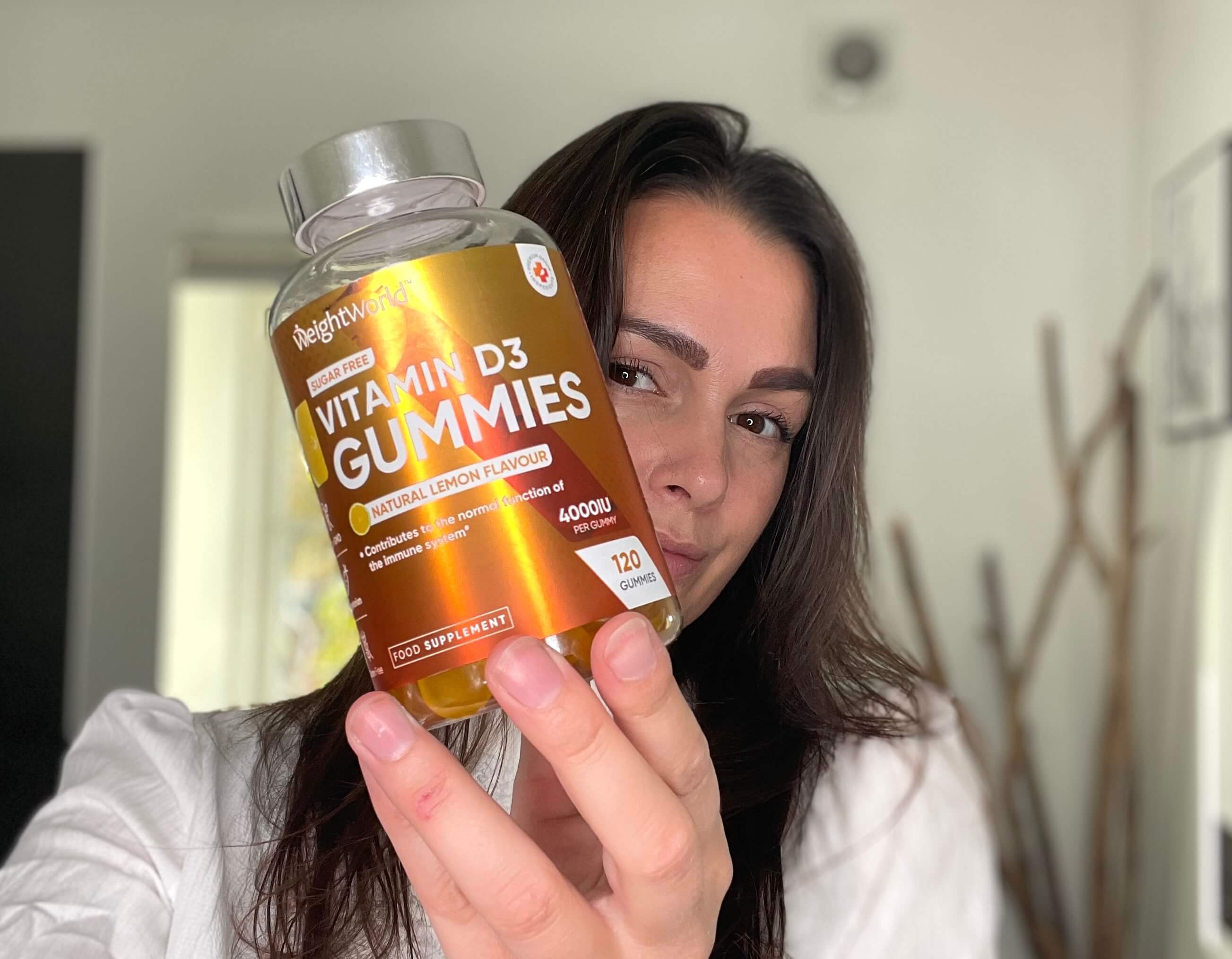 Kvinde der står med D3-Vitamin Gummies foran sig