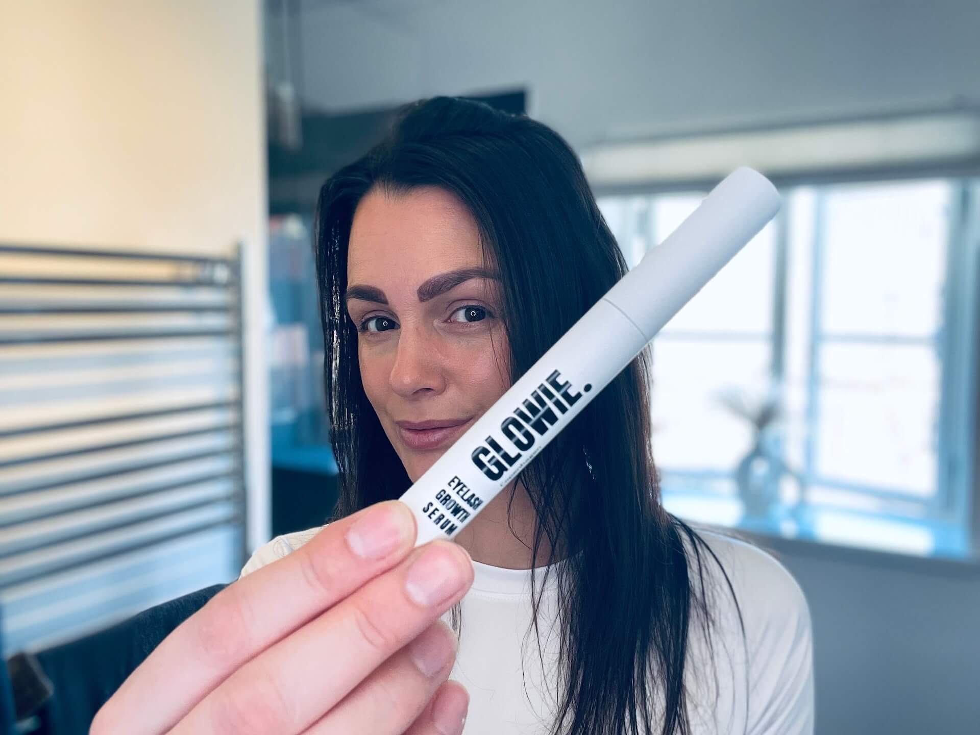 Kvinde der står med Glowie Eyelash Growth Serum