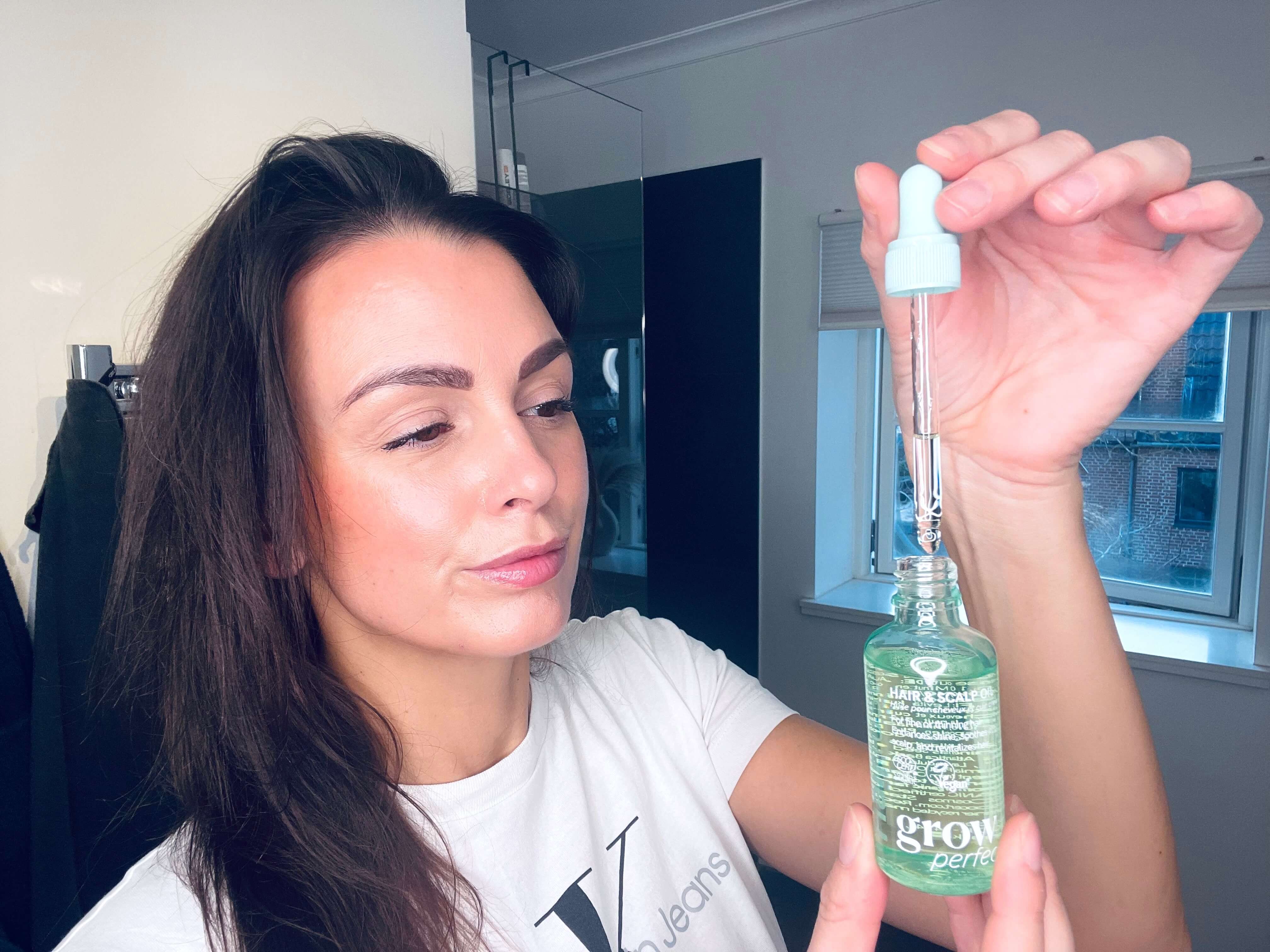 Kvinde der står med grow perfect hovedbundsolie fra Hairlust