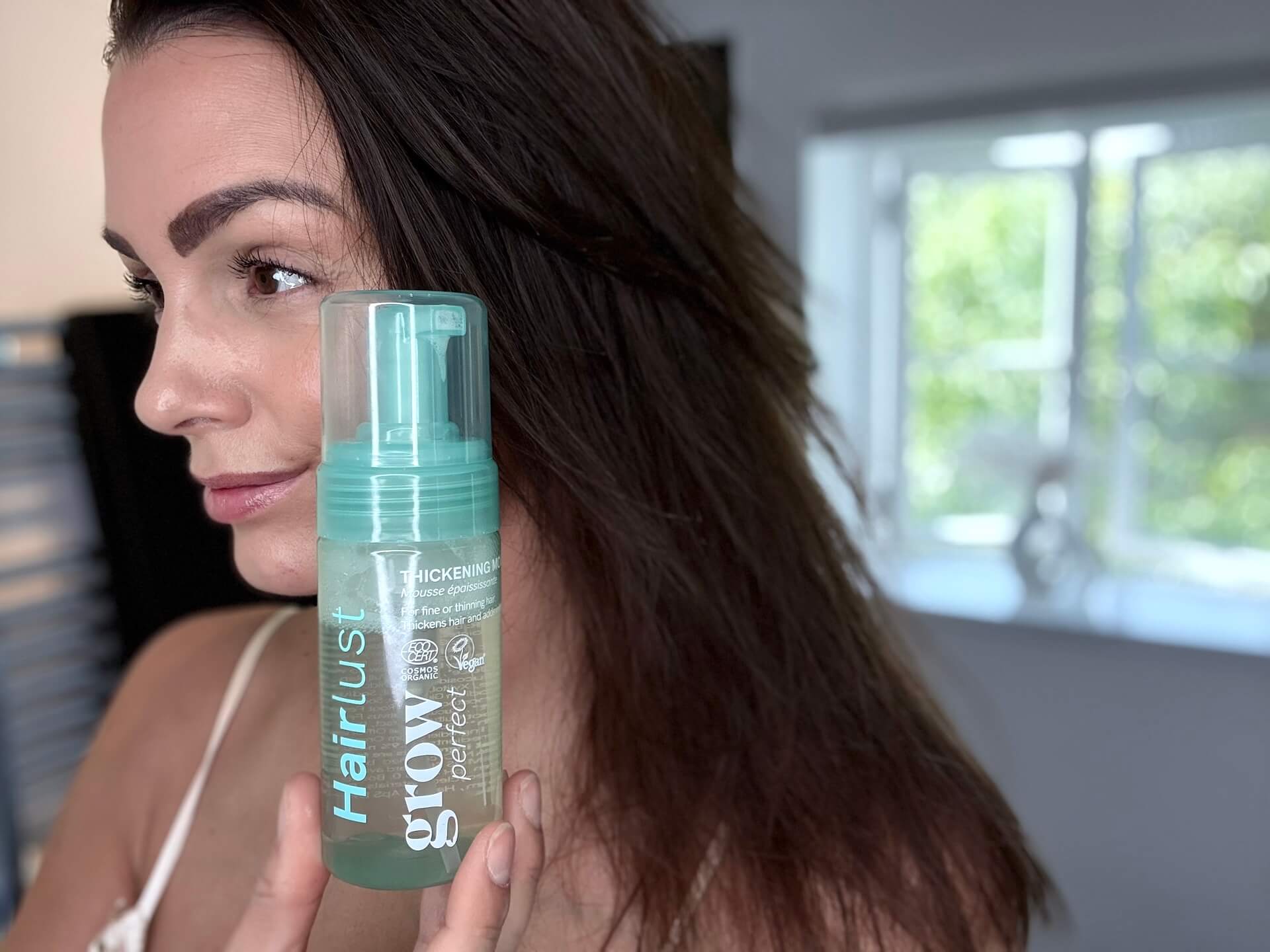 Kvinde der står med Hairlust Grow Perfect Thickening Mousse