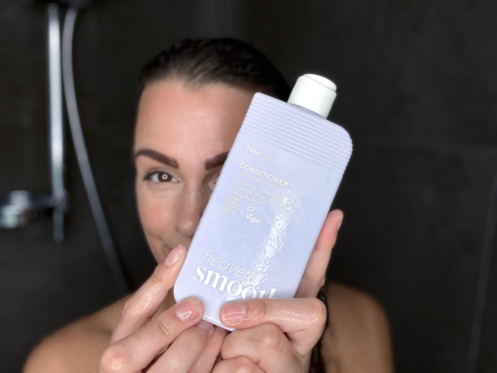 Kvinde der står med Hairlust Heavenly Smooth Conditioner i badet