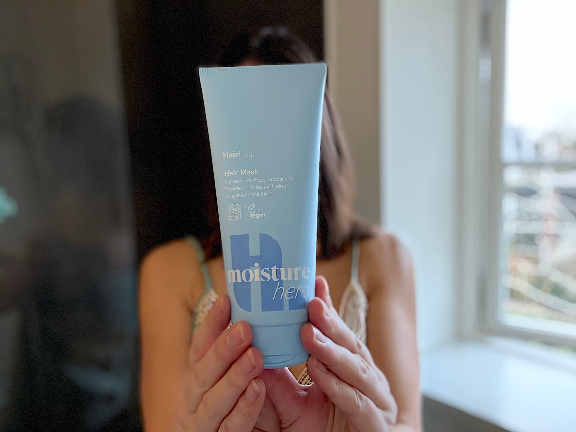 Kvinde der står med Hairlust Moisture Hero hårkur