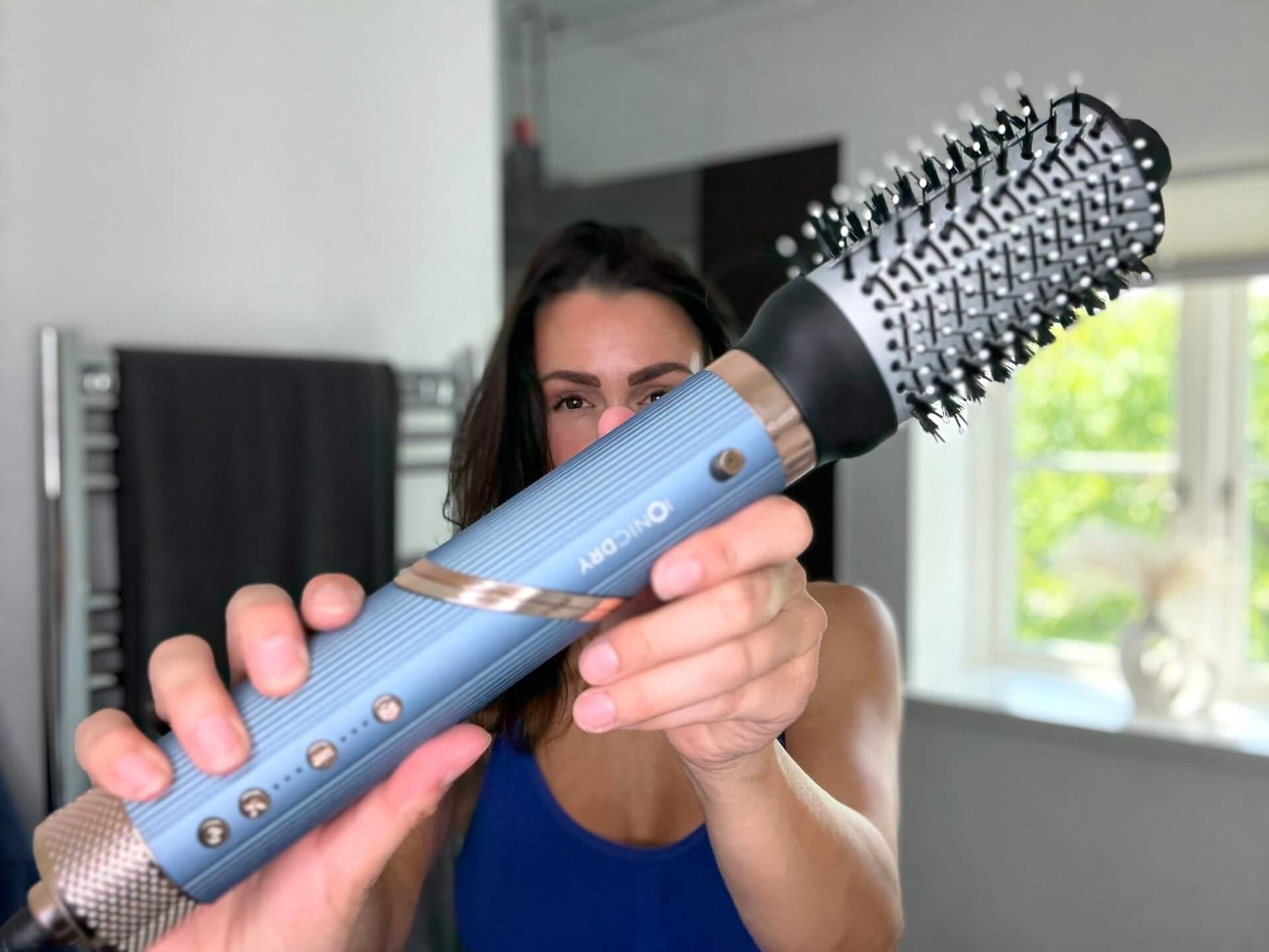 Kvinde der står med MultiStyler Pro fra Ionic Dry med volumenbørste på