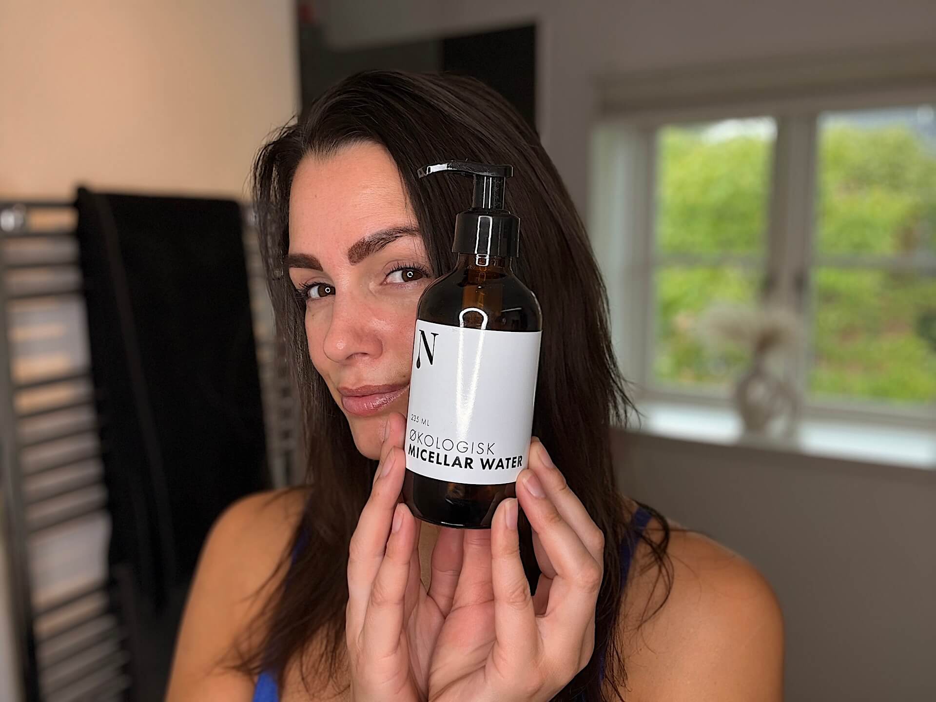 Kvinde der står med Naturligolie Micellar Water på badeværelse