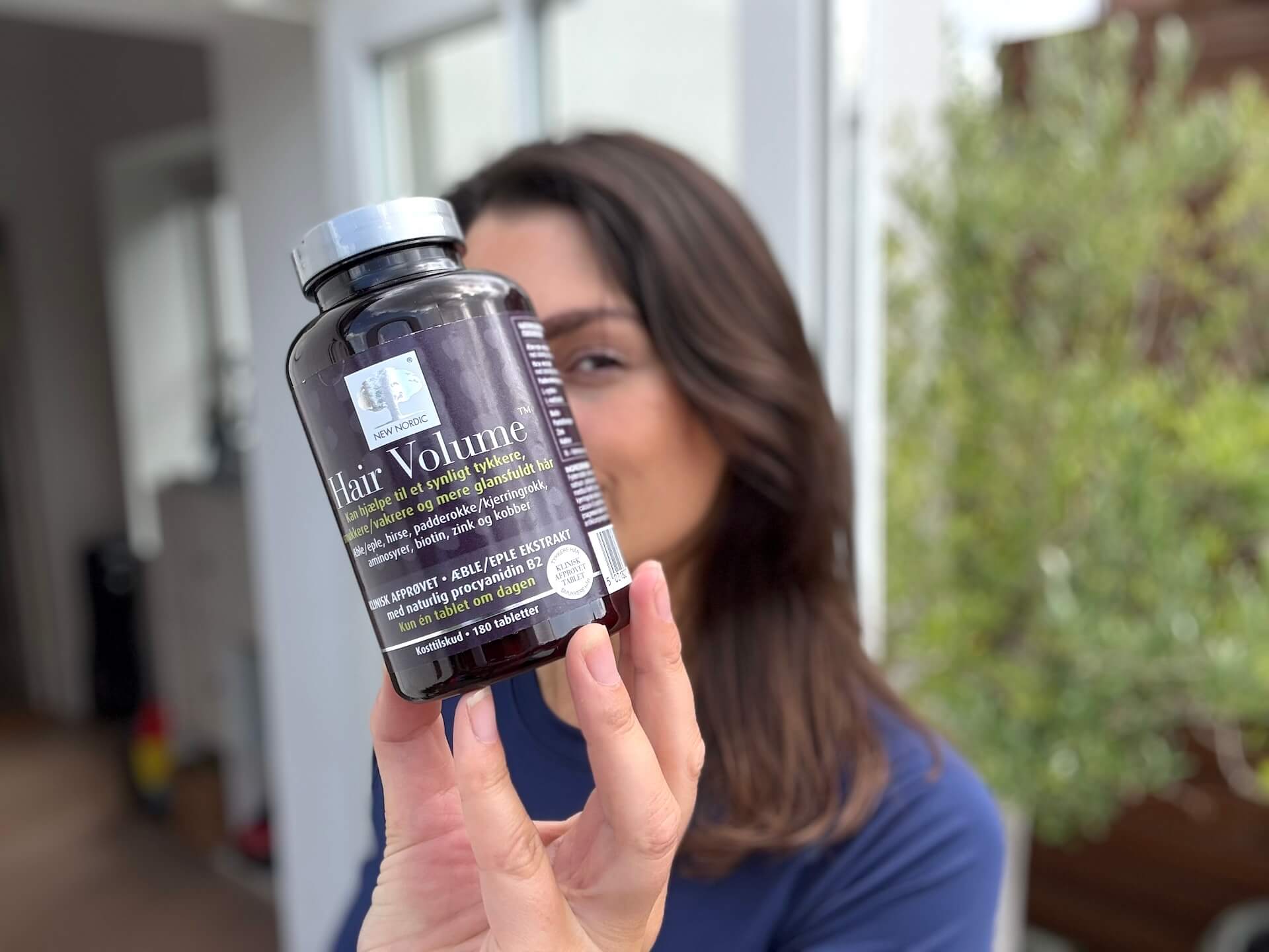 Kvinde der står med New Nordic Hair Volume i hånden