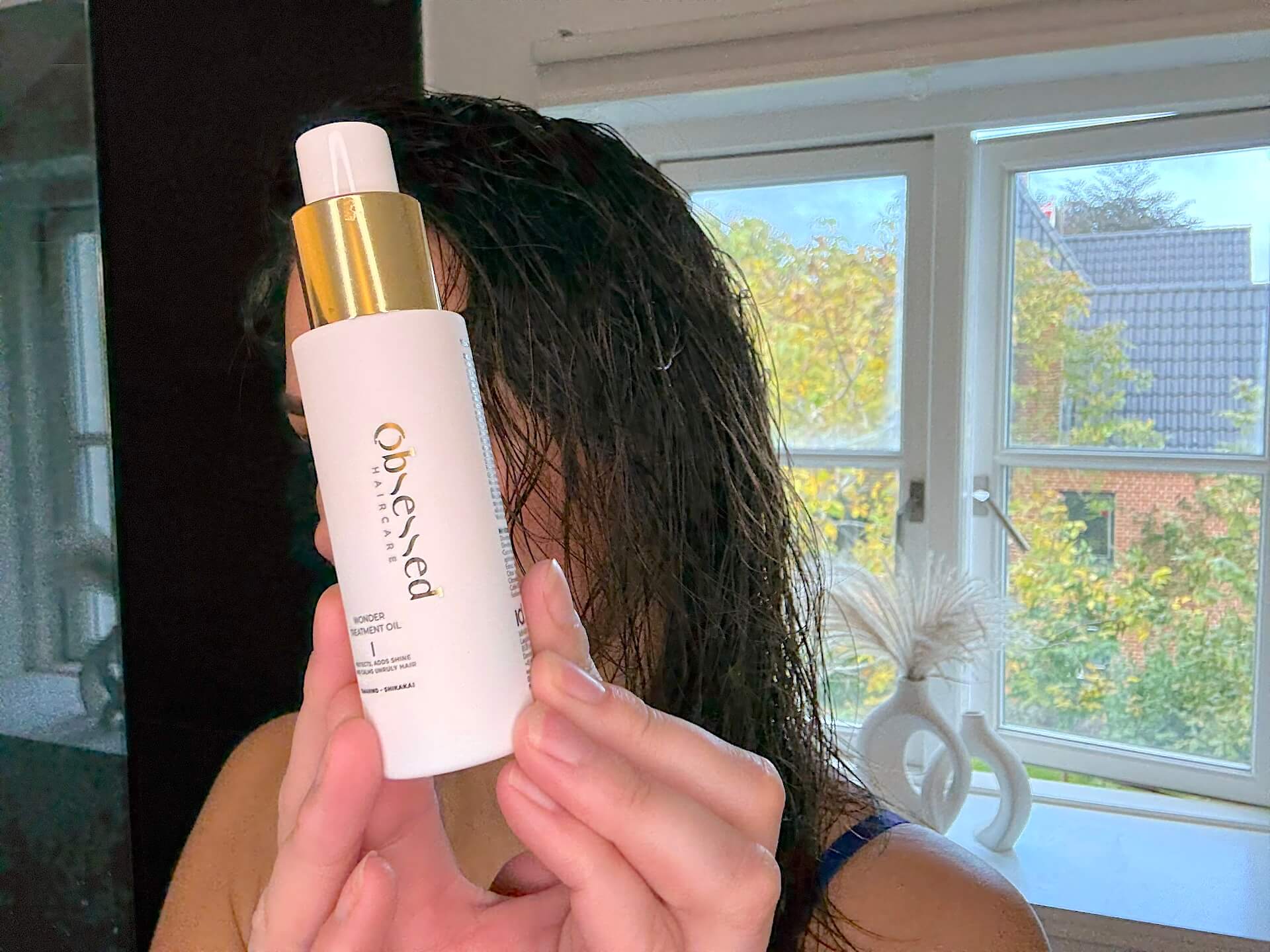 Kvinde der står med Obsessed Haircare Wonder Treatment Oil