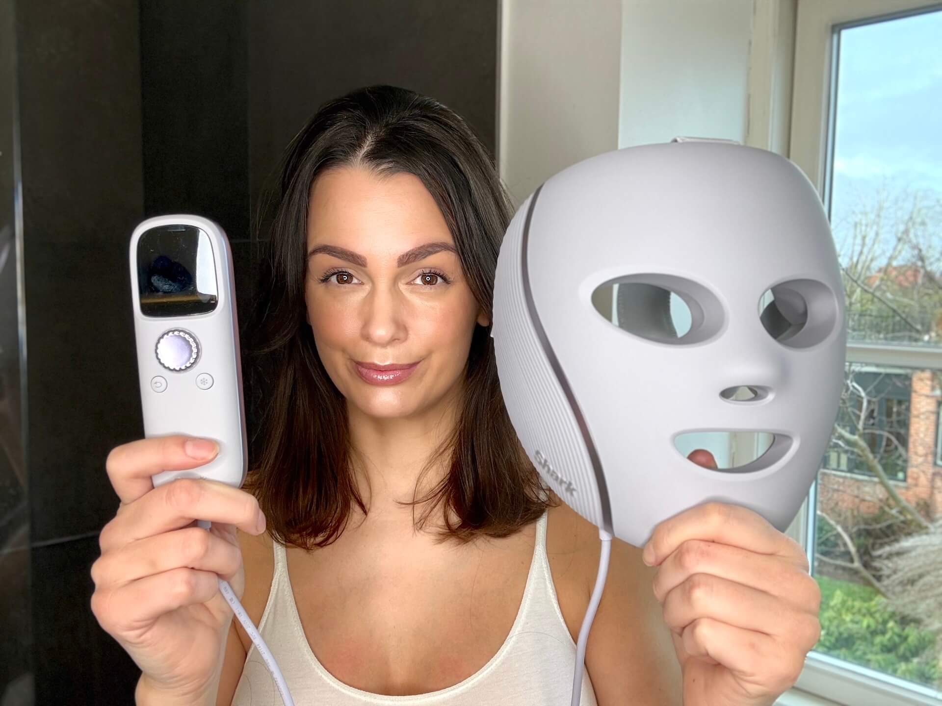 Kvinde der står med Shark CryoGlow LED Face Mask