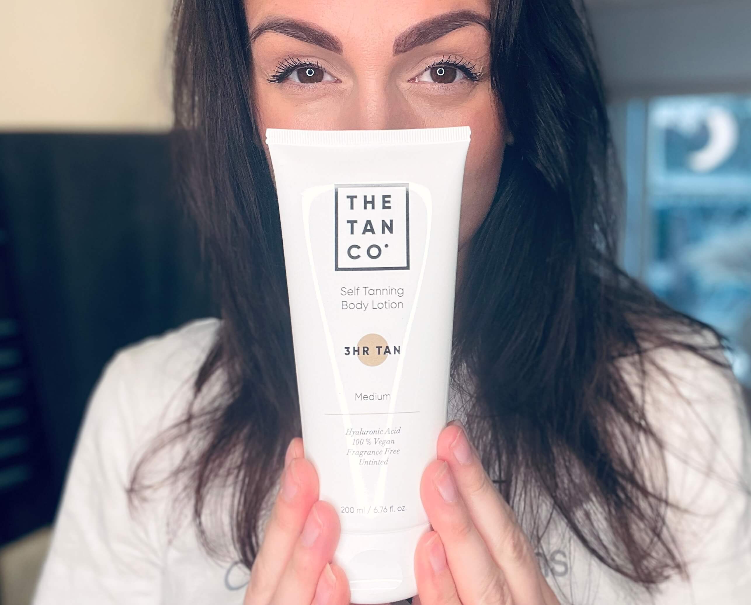 Kvinde der står med The Tan Co selvbruner lotion