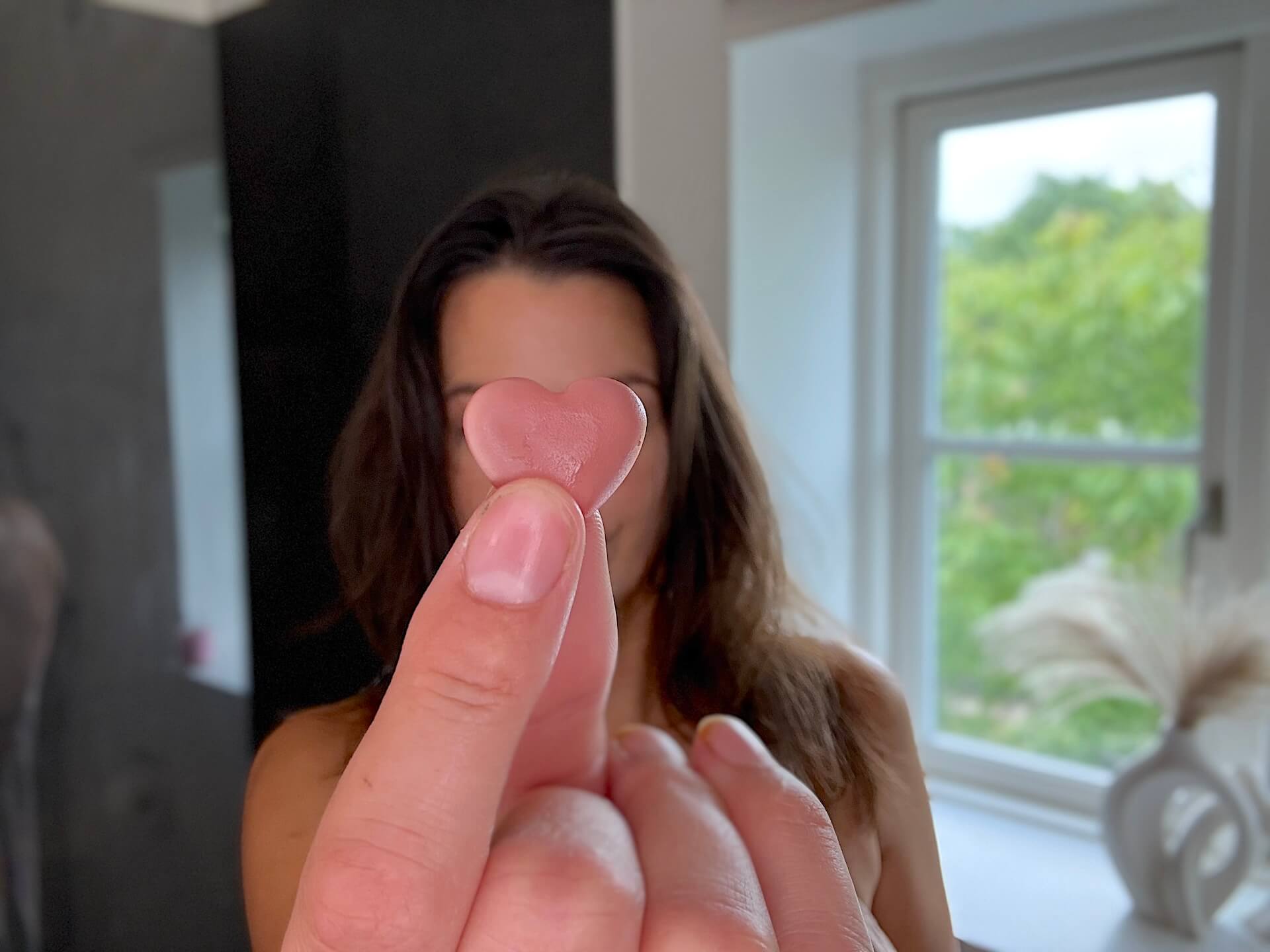Kvinde der står med Yuaia Haircare Hair Vitamins vingummi